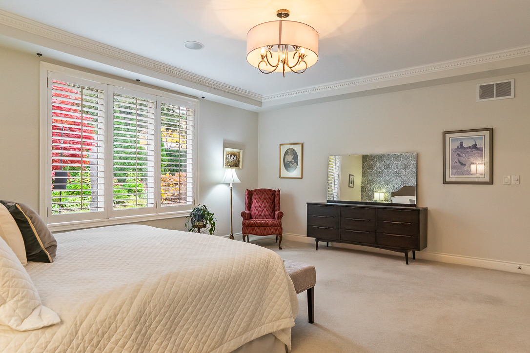 Bright bedroom featuring a bed, dresser, and armchair by a window