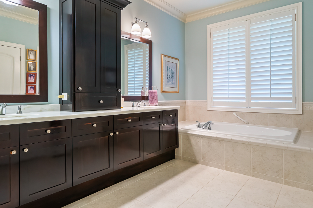 Elegant bathroom with dark cabinetry, a soaking tub, and light blue walls