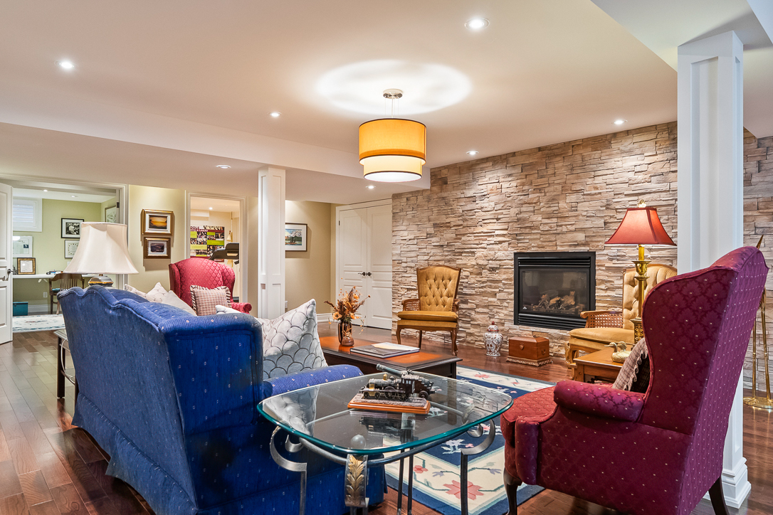 Cozy living room with stone fireplace, colorful chairs, and glass coffee table