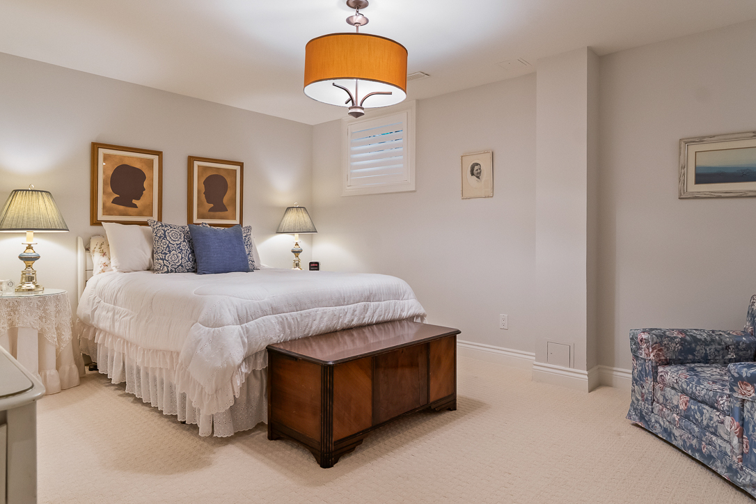 Cozy bedroom with a white bed, decorative pillows, and vintage artwork