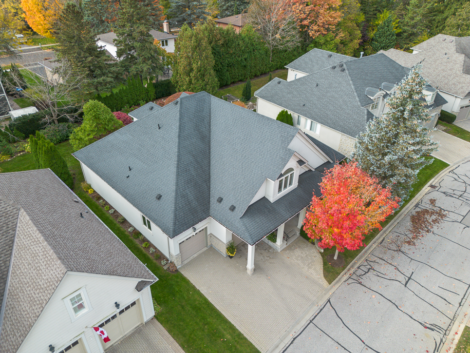 Aerial view of a house with a gray roof and colorful autumn trees