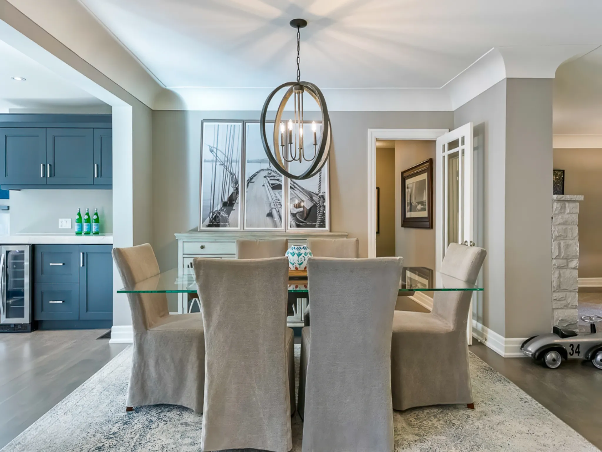 Modern dining room with glass table, beige chairs, and stylish chandelier