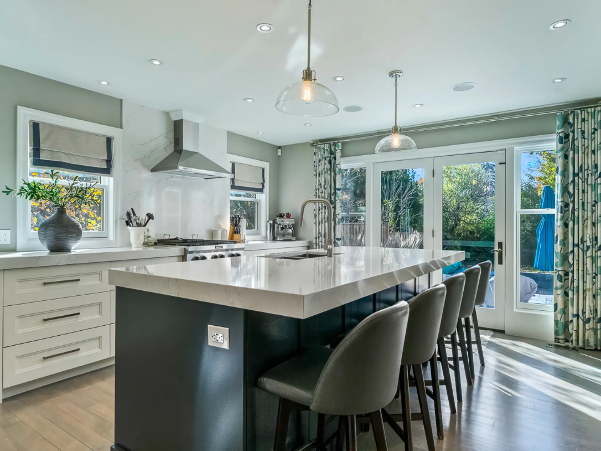 Modern kitchen with a large island, bar stools, and natural light.