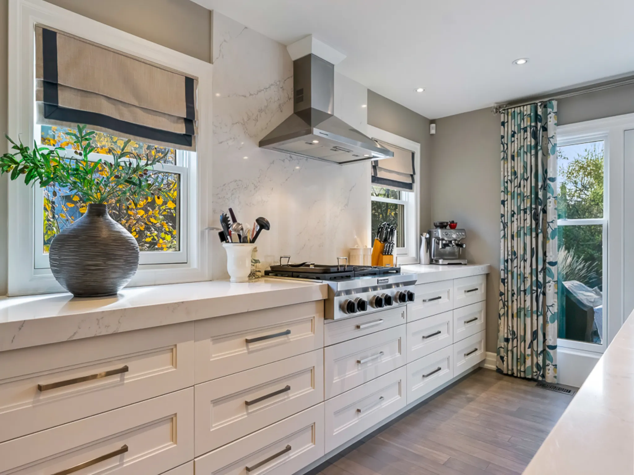 Modern kitchen with white cabinetry, stainless steel appliances, and floral curtains