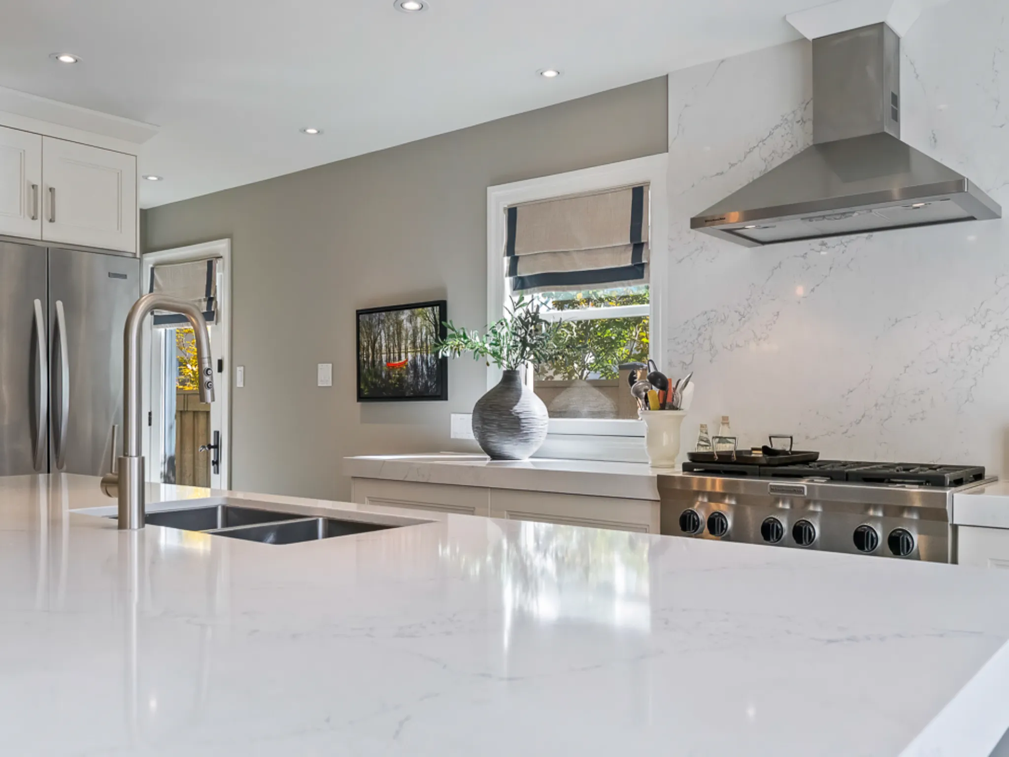 Modern kitchen with white countertops, stainless steel appliances, and natural light