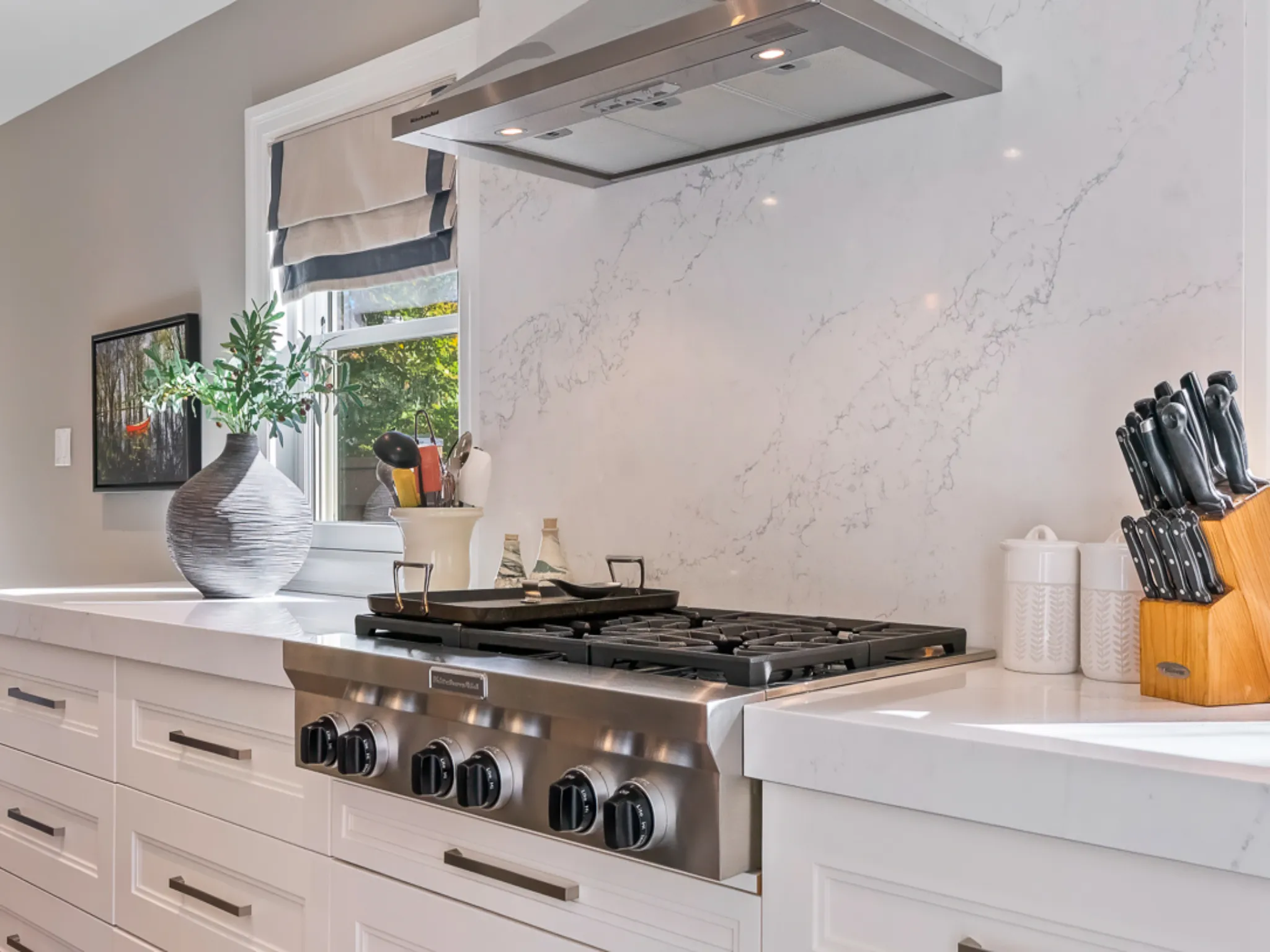 Modern kitchen with a gas stove, white cabinetry, and a window view