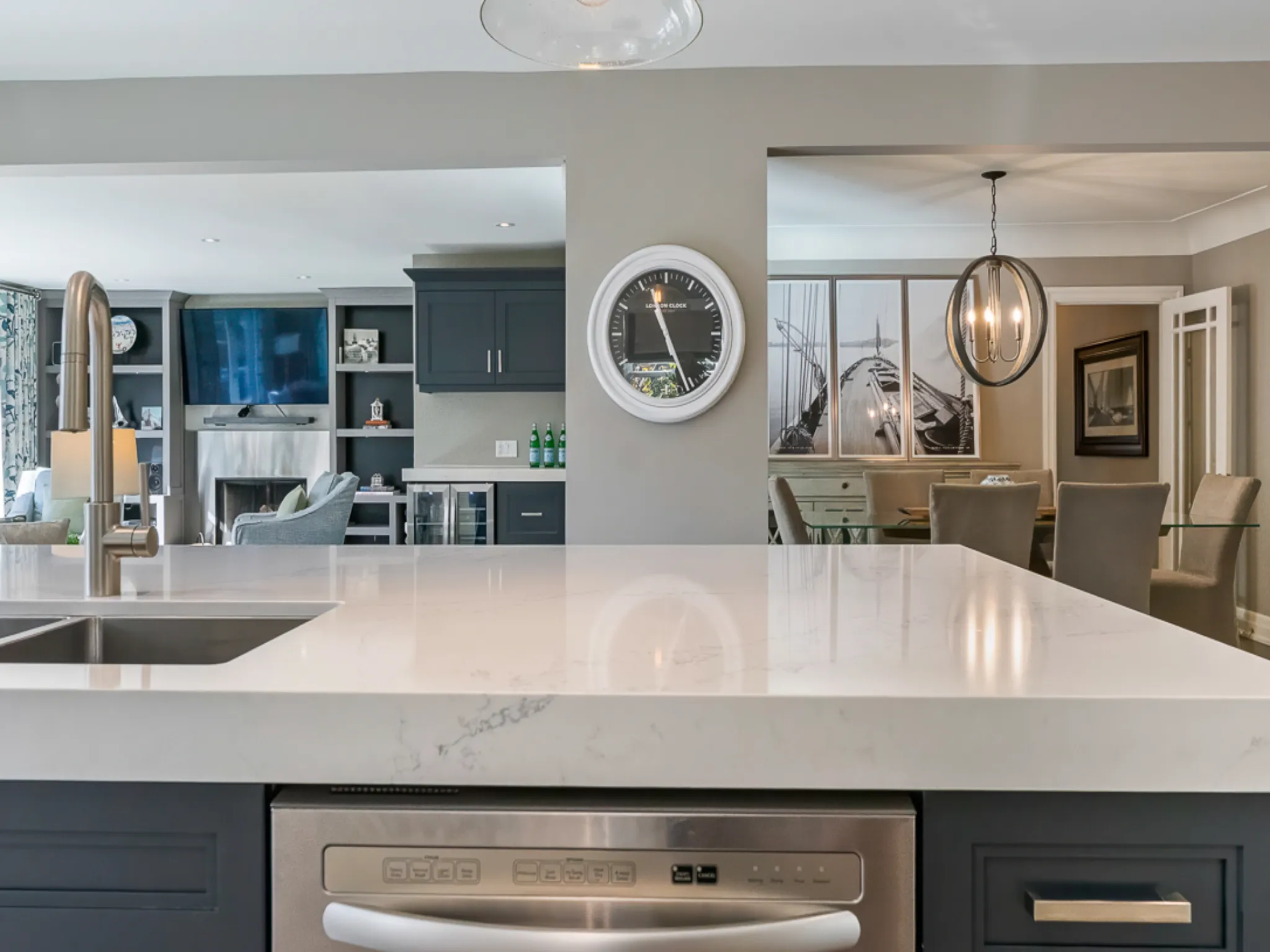 Modern kitchen with white countertop, dark cabinetry, and open layout.