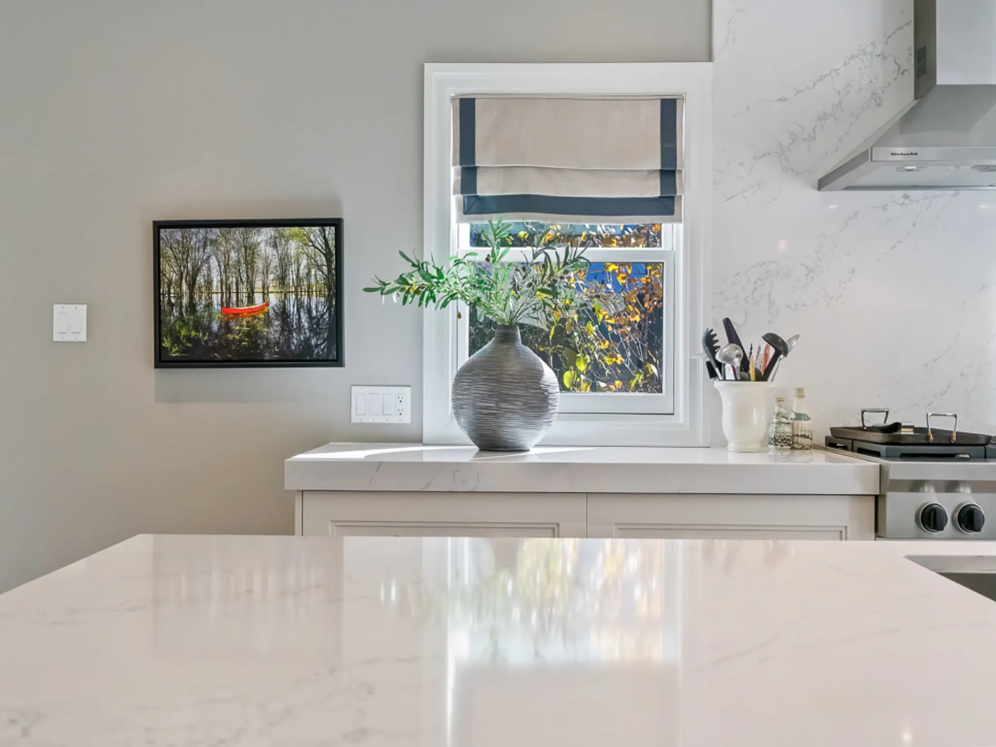 Modern kitchen with marble countertop, vase, and artwork on the wall
