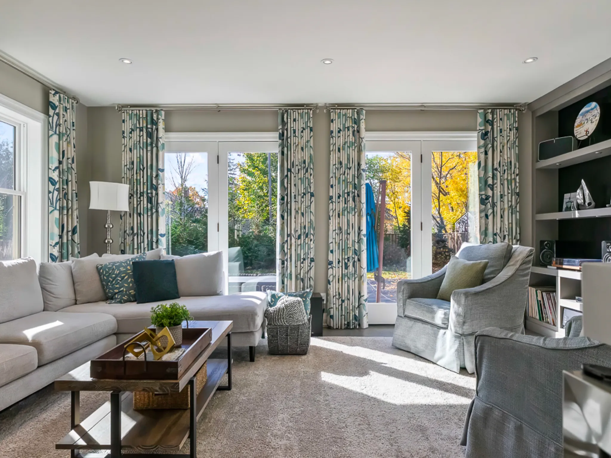 Bright living room with large windows, light curtains, and modern furniture
