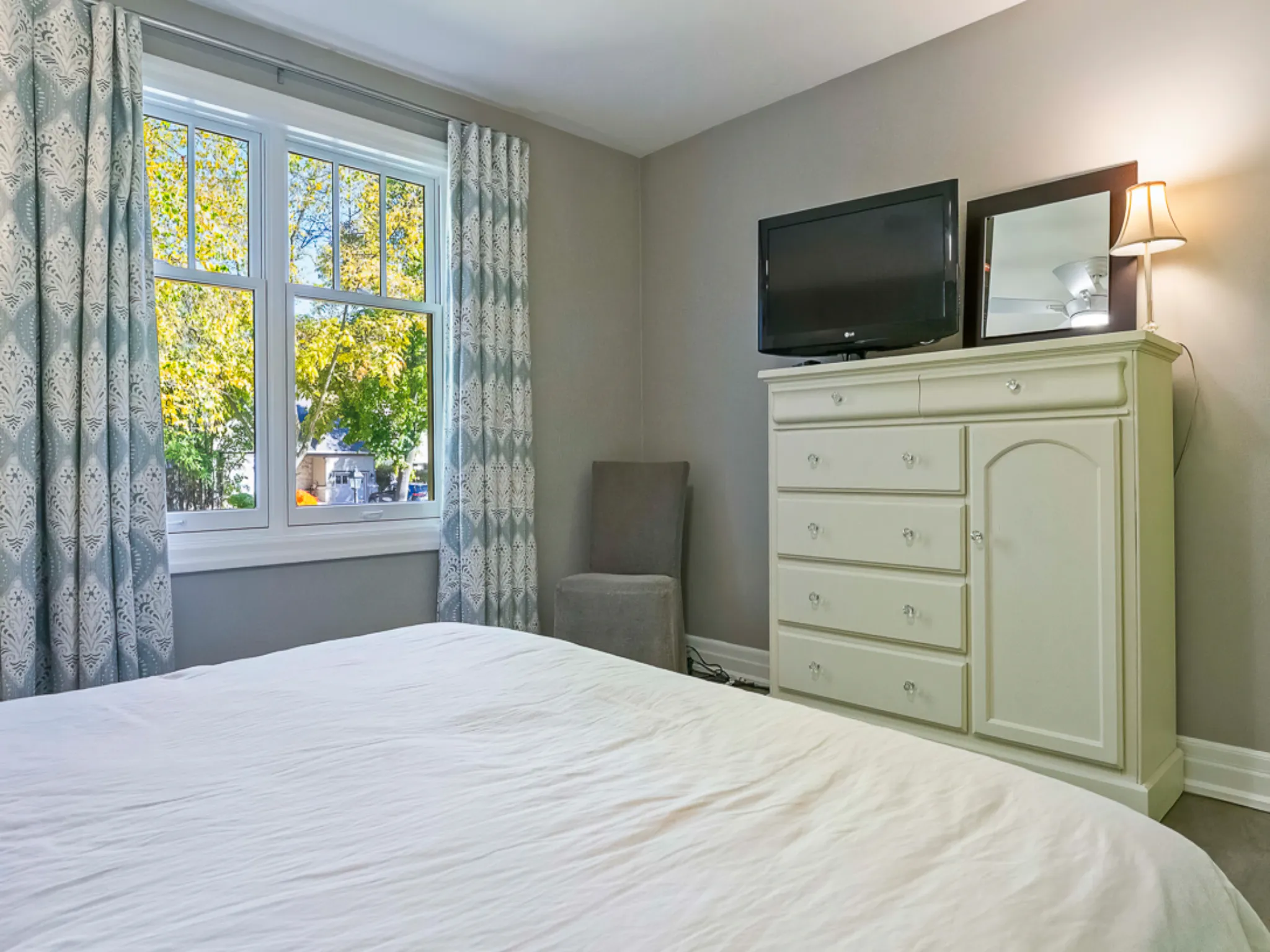 Cozy master bedroom with a bed, dresser, and window view