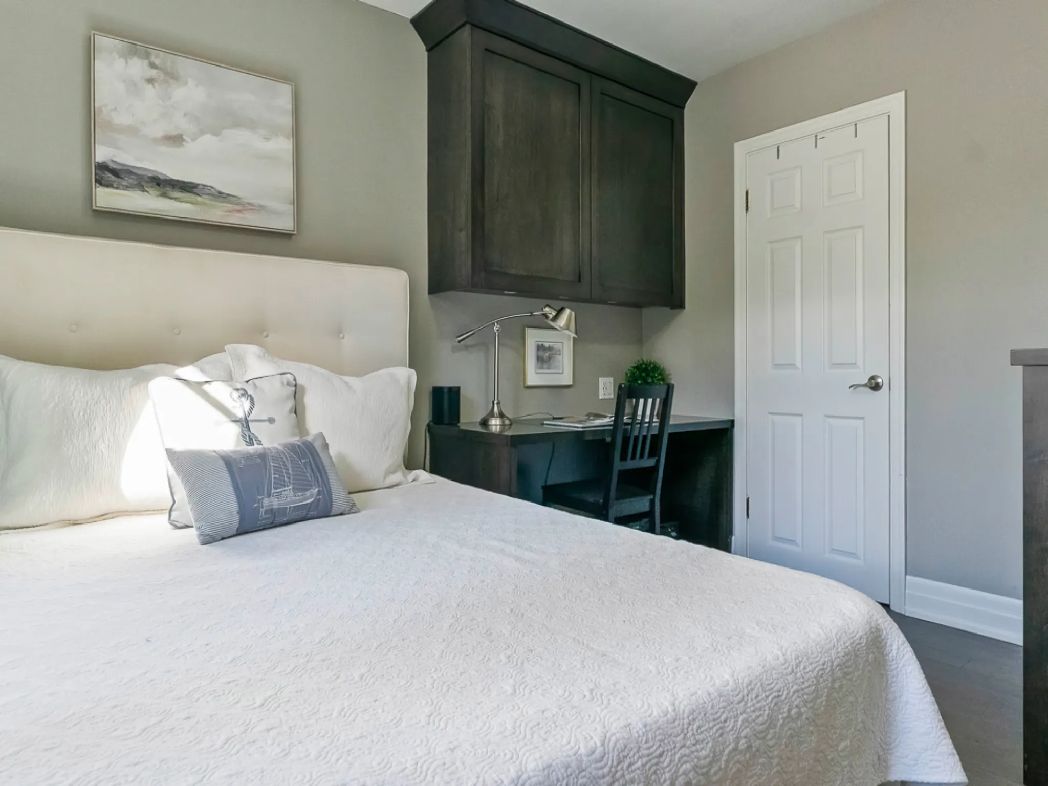 Cozy master bedroom with a bed, desk, and light gray walls