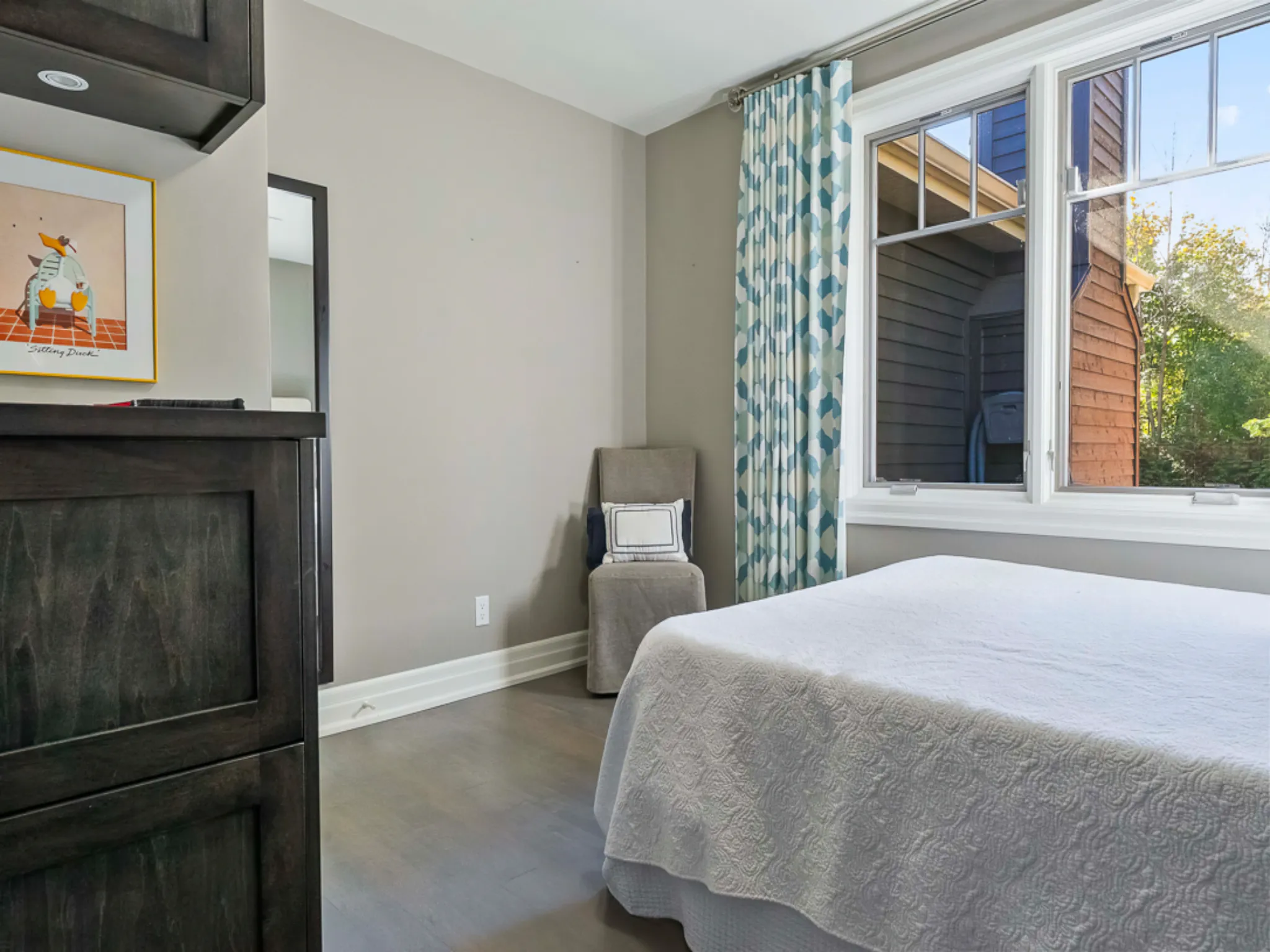 Bright master bedroom with a bed, window, and patterned curtains