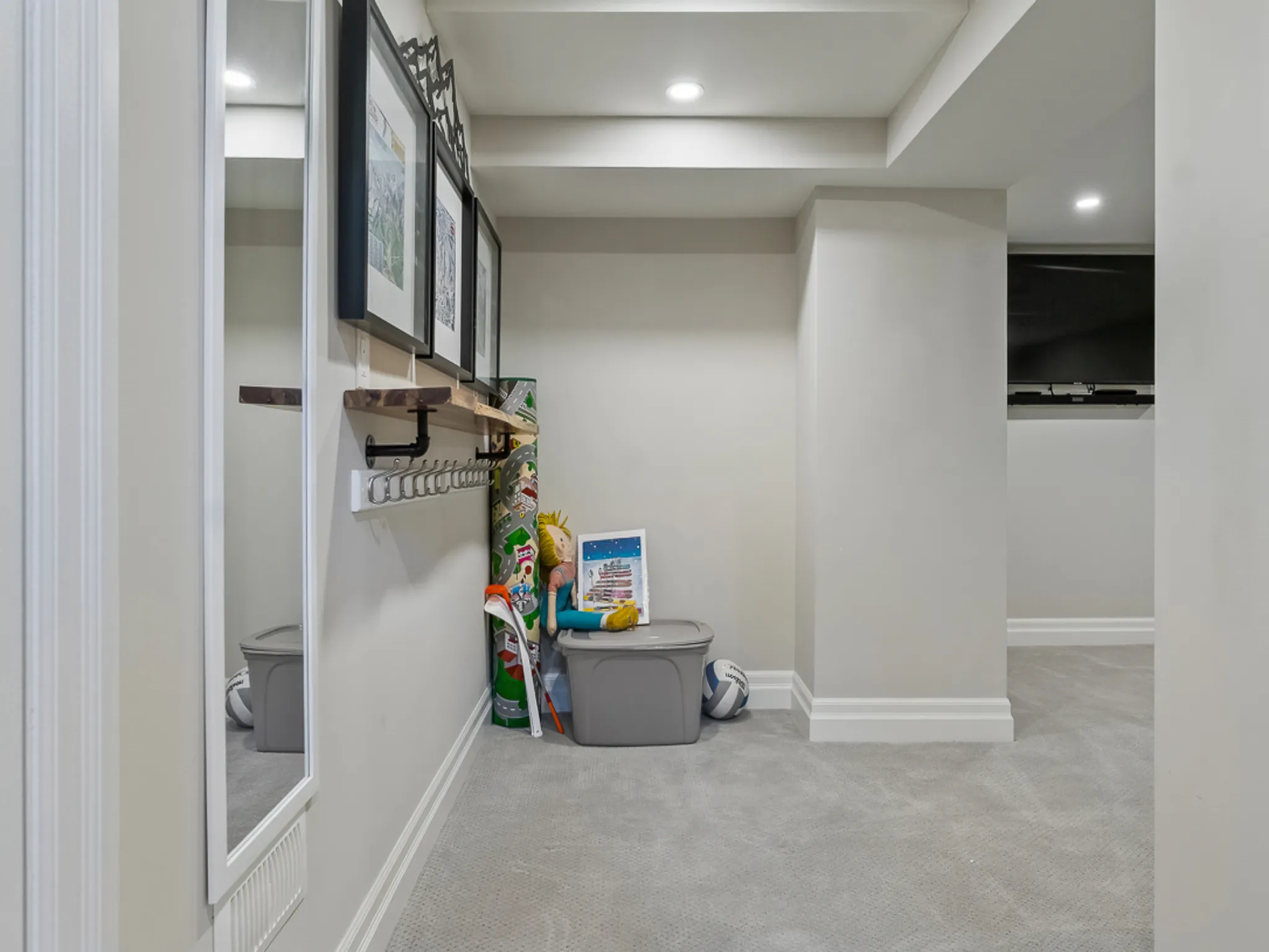 Bright basement hallway with storage bins and wall hooks