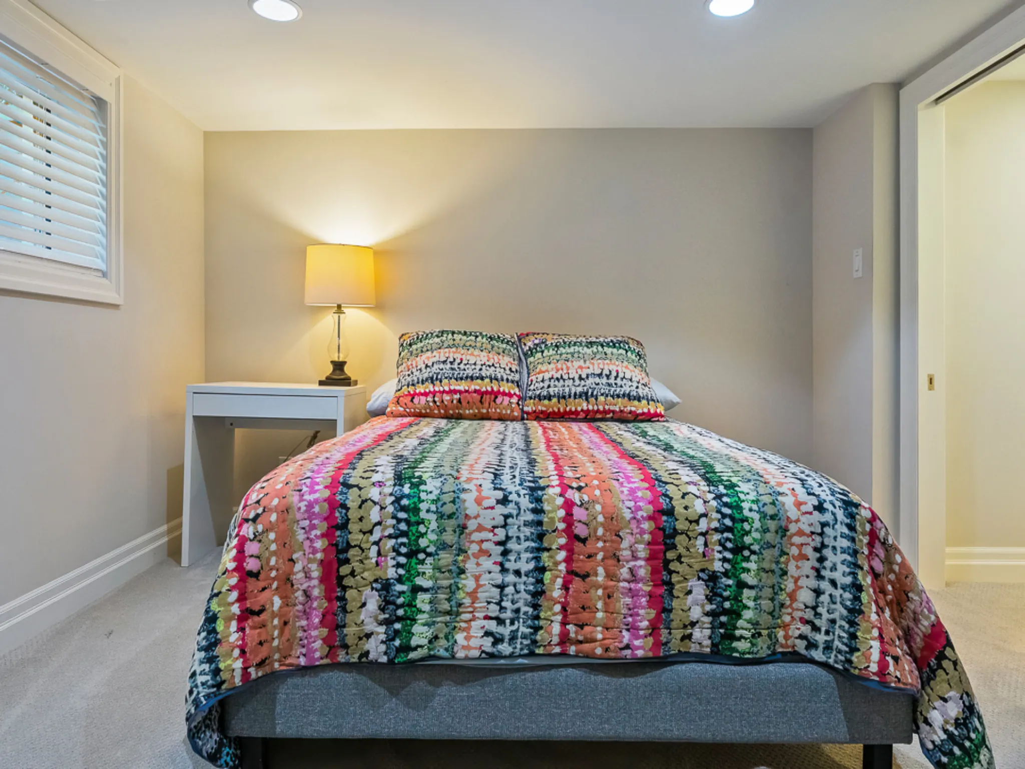 Cozy guest bedroom with colorful striped bedding and bedside lamp