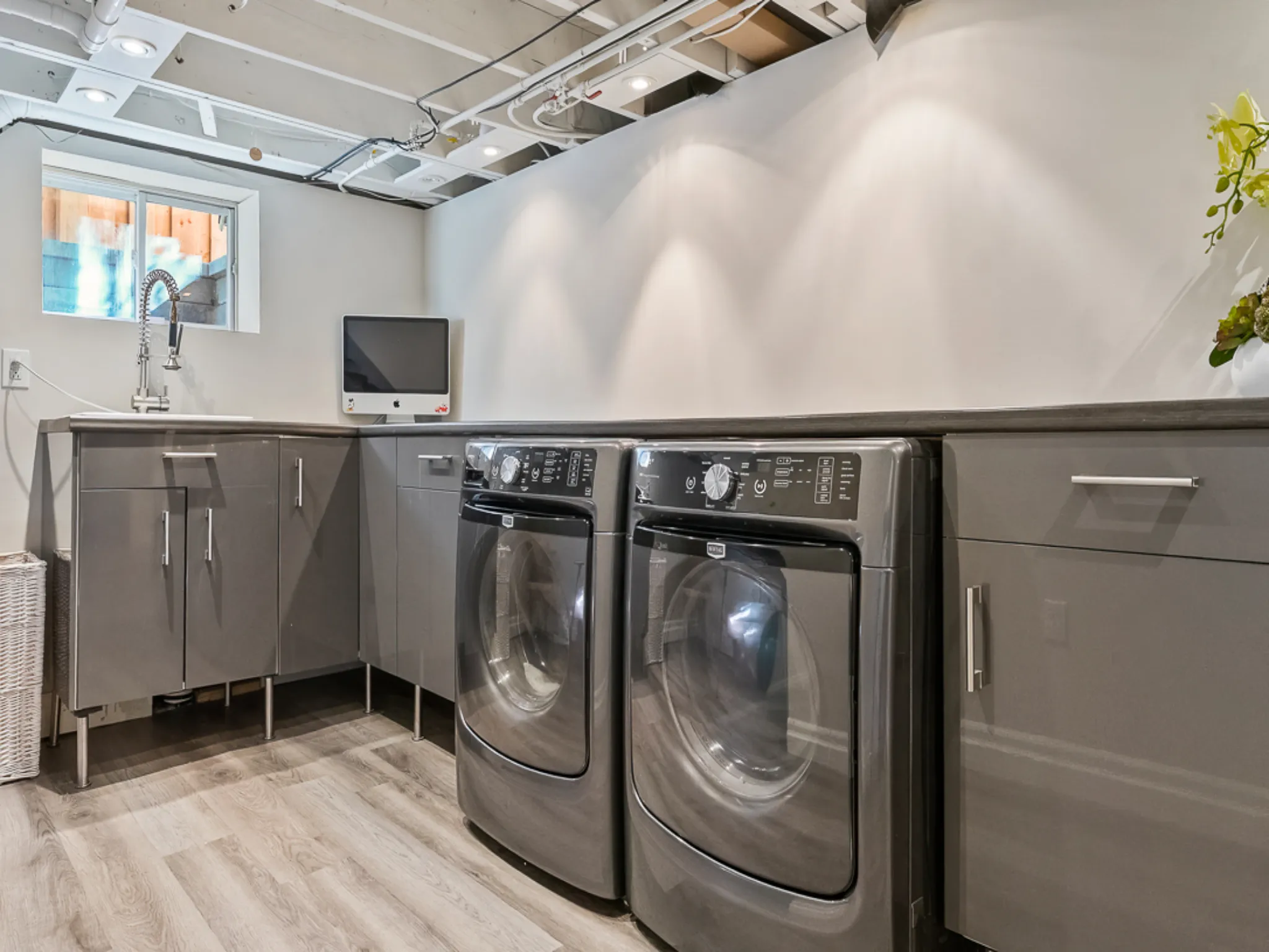 Modern laundry room with gray cabinets and two front-loading washers