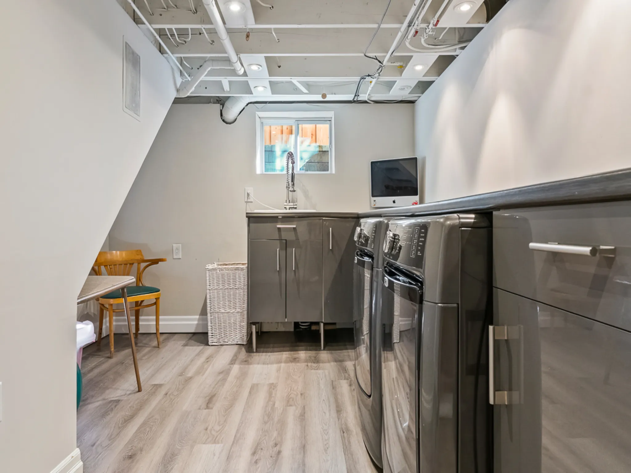 Modern laundry room with stainless steel appliances and light wood flooring