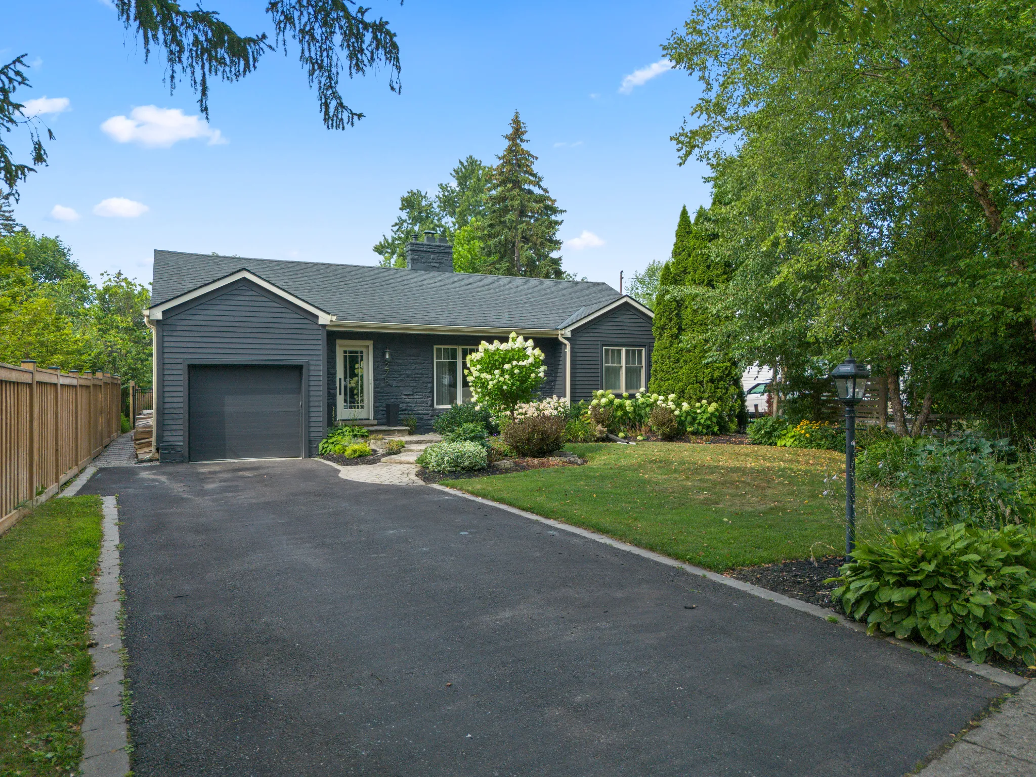 Single-story gray house with landscaped yard and driveway
