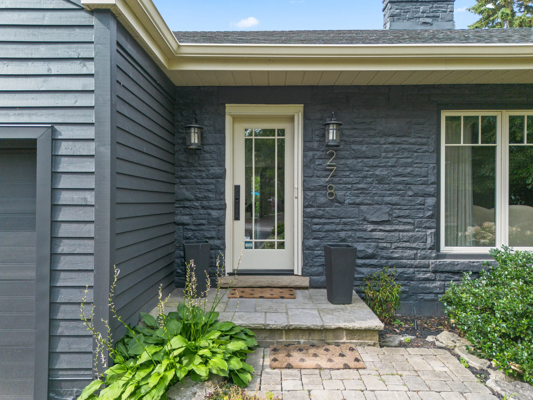 Modern home entrance with stone walls and greenery
