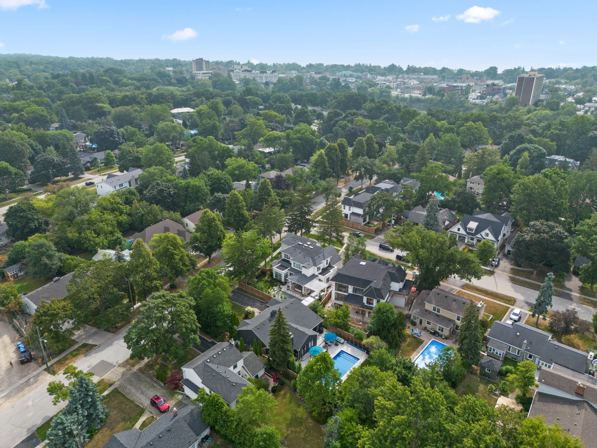 Aerial view of a suburban neighborhood with trees and houses, including pools