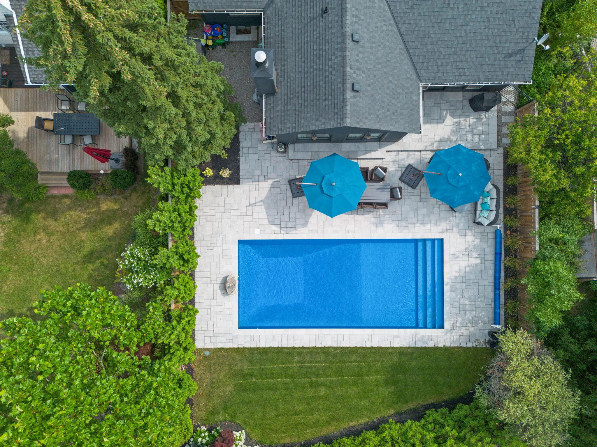 Aerial view of a backyard with a blue pool and patio umbrellas
