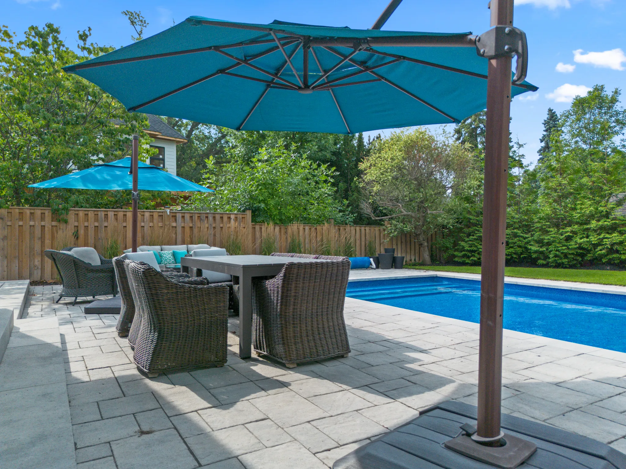 Patio area with a pool, outdoor furniture, and teal umbrellas