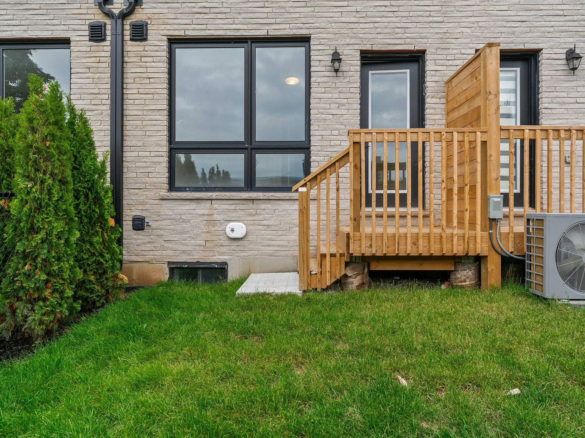Backyard view featuring a wooden deck, grass, and air conditioning unit.