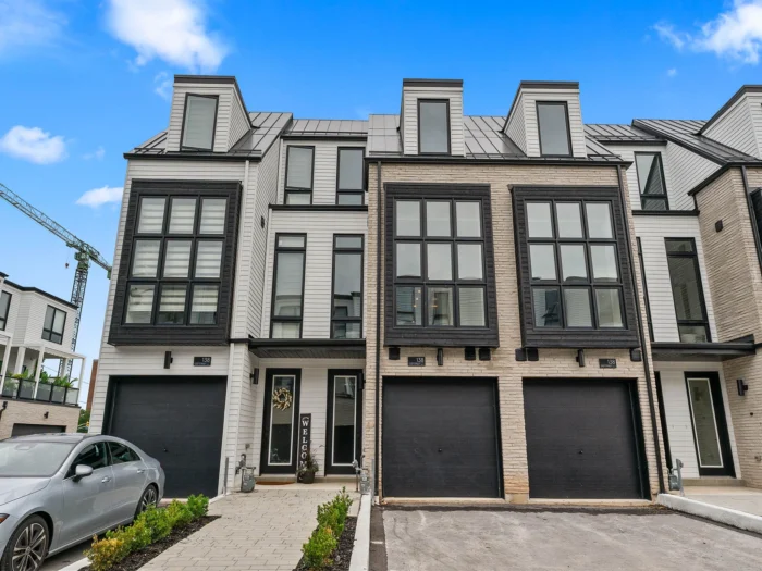Modern townhouses with large windows and garages, blue sky above