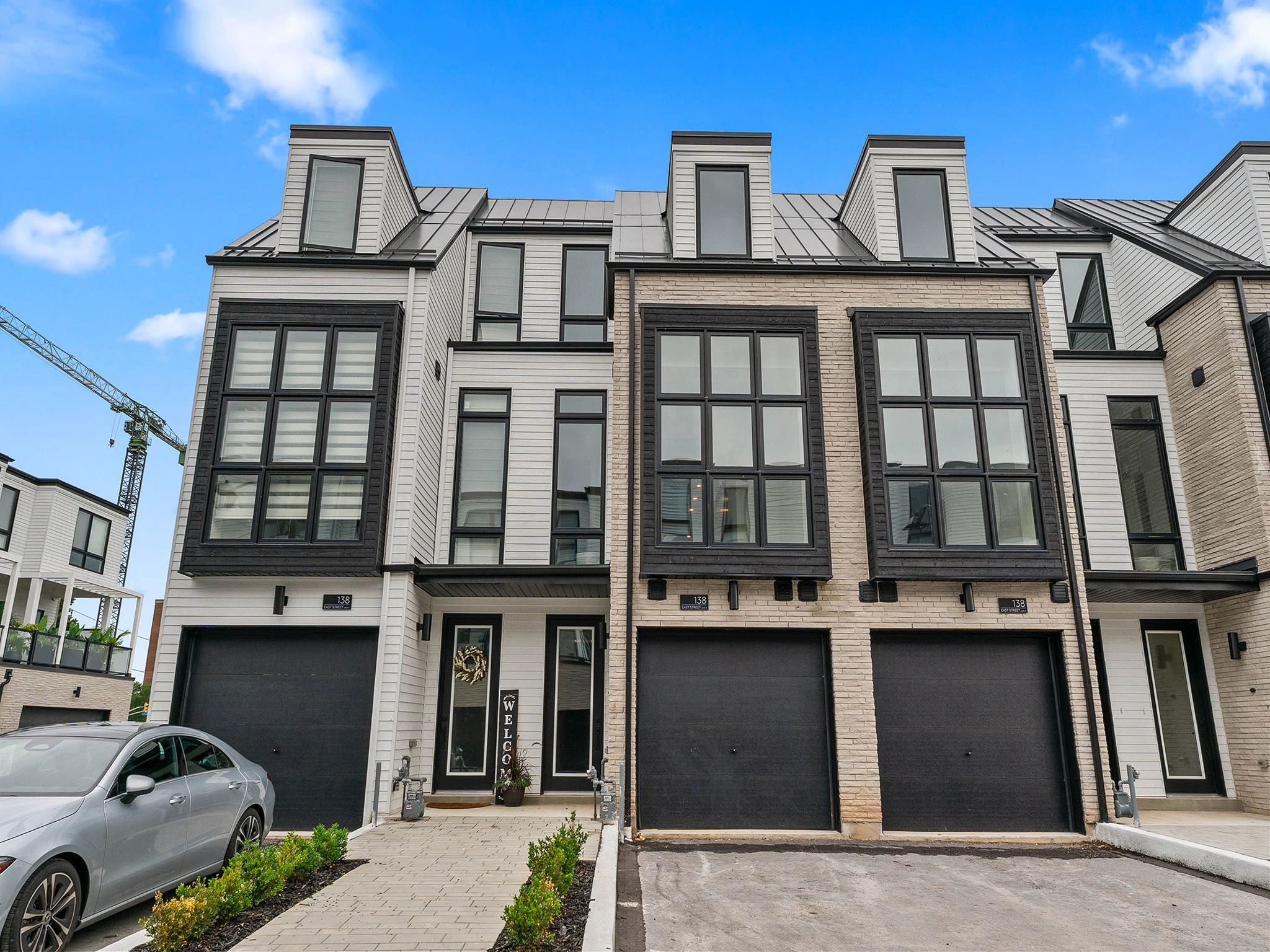 Modern townhouses with large windows and garages, blue sky above