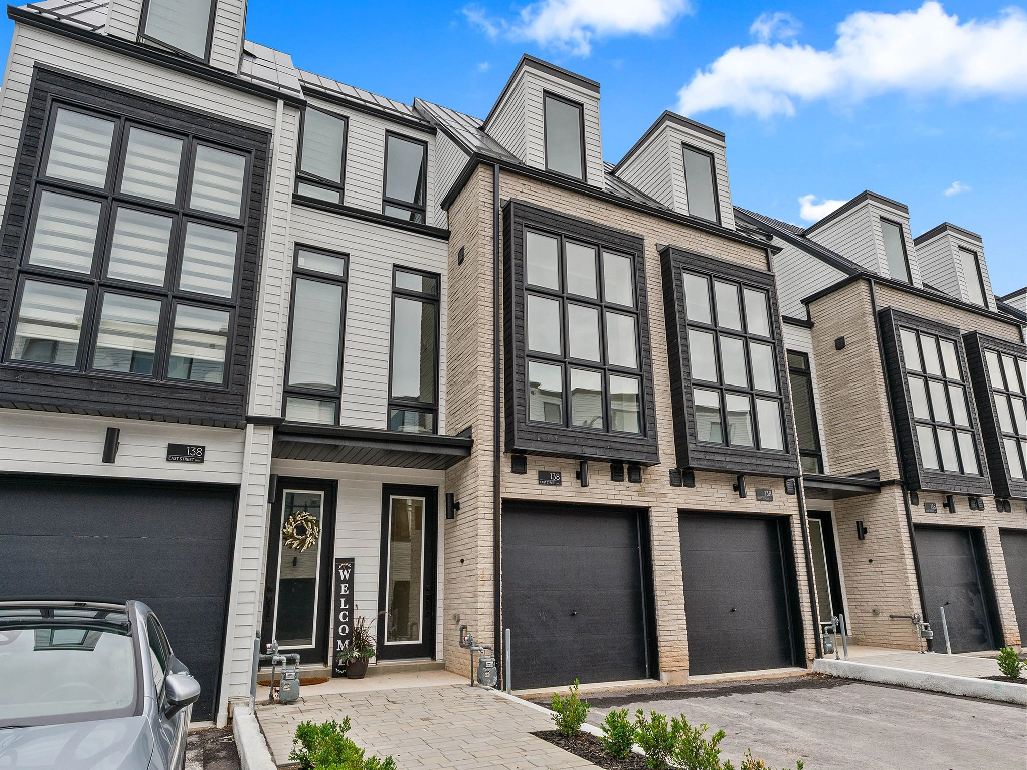 Modern townhouses with large windows and garages under a blue sky