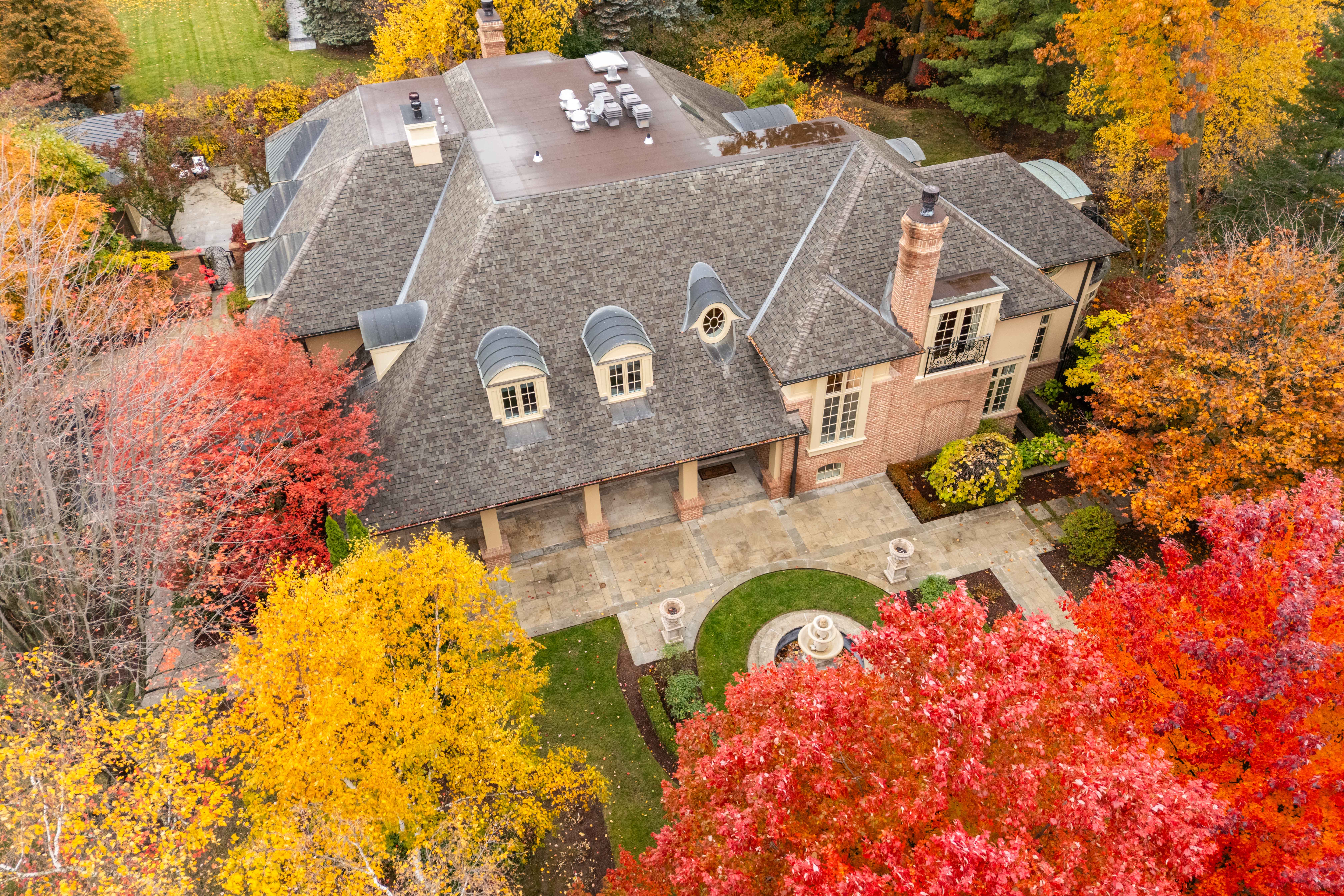 Aerial view of a large house surrounded by vibrant autumn foliage