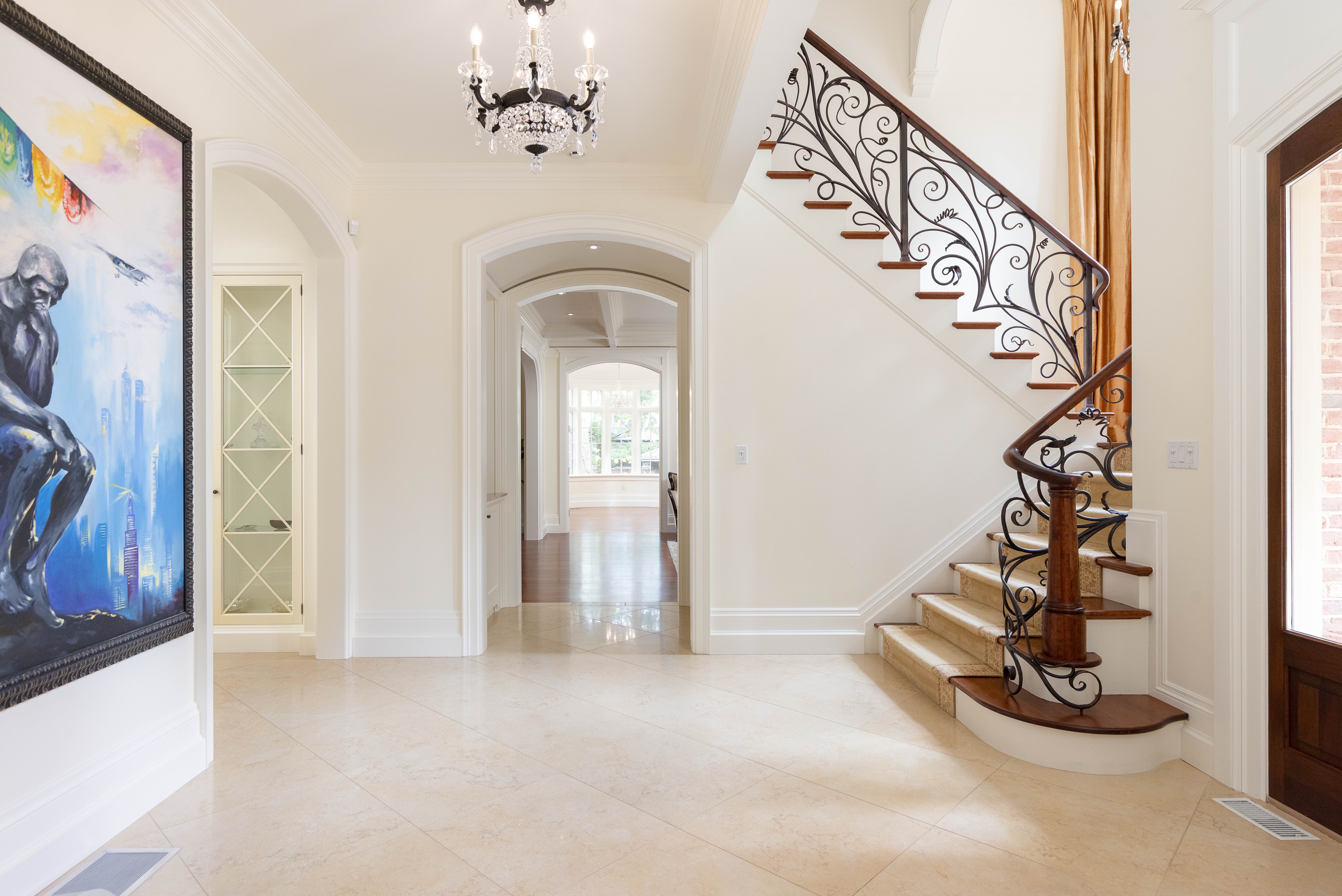 Elegant foyer with a staircase, chandelier, and modern artwork on the wall