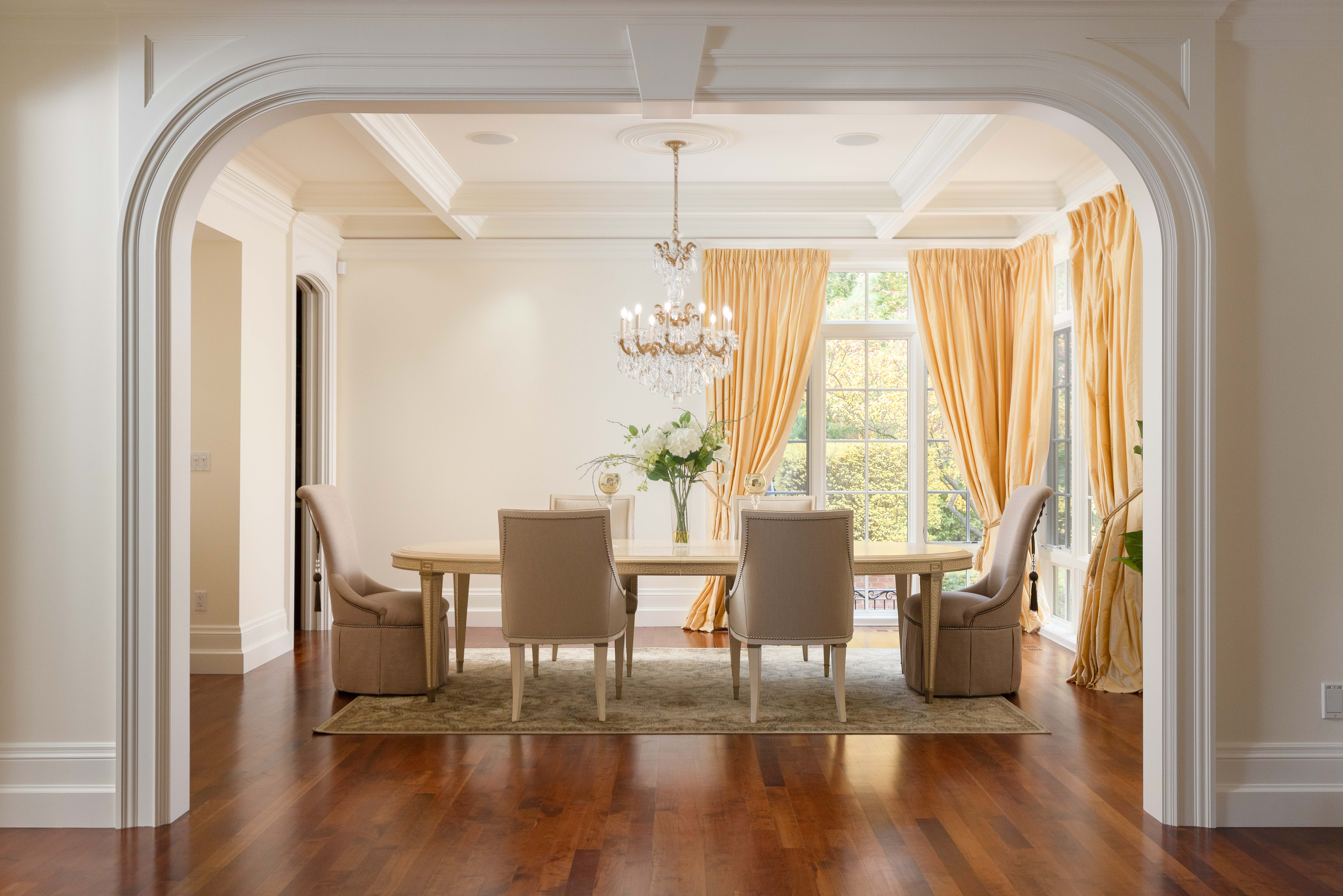 Elegant dining room with wooden table, upholstered chairs, and large windows.