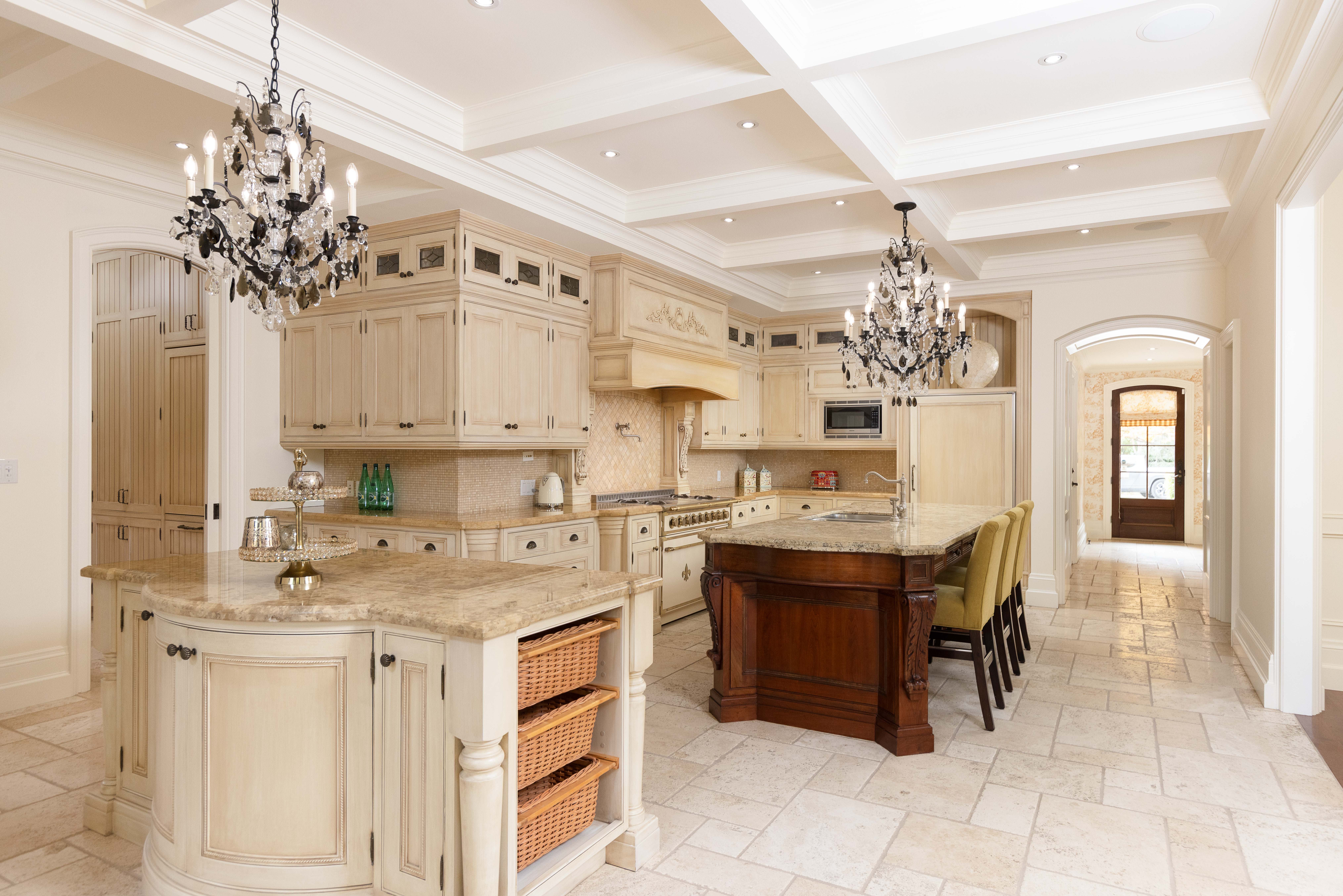 Elegant kitchen with cream cabinets, chandeliers, and a large island
