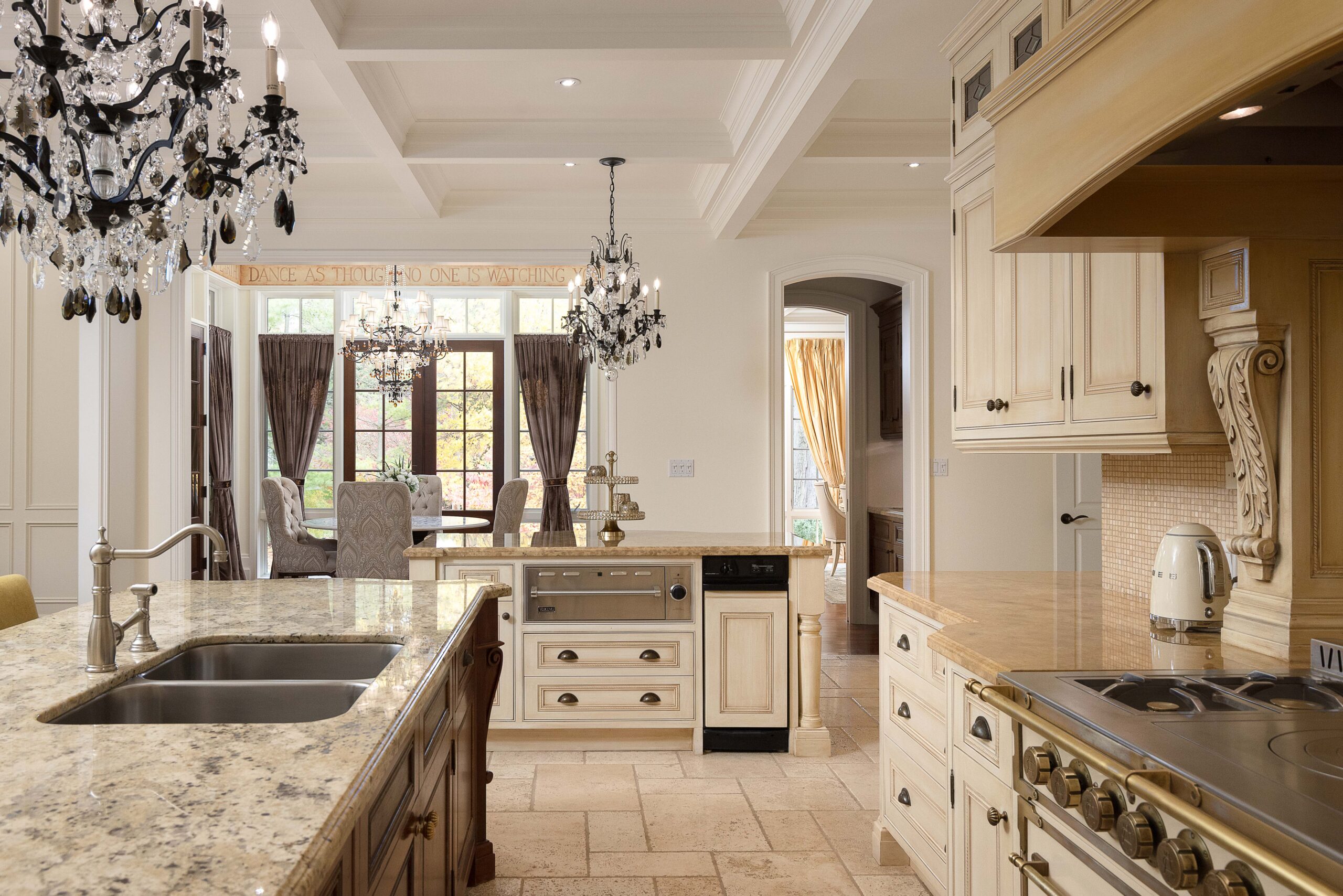 Elegant kitchen with granite countertops and chandeliers, featuring light cabinetry