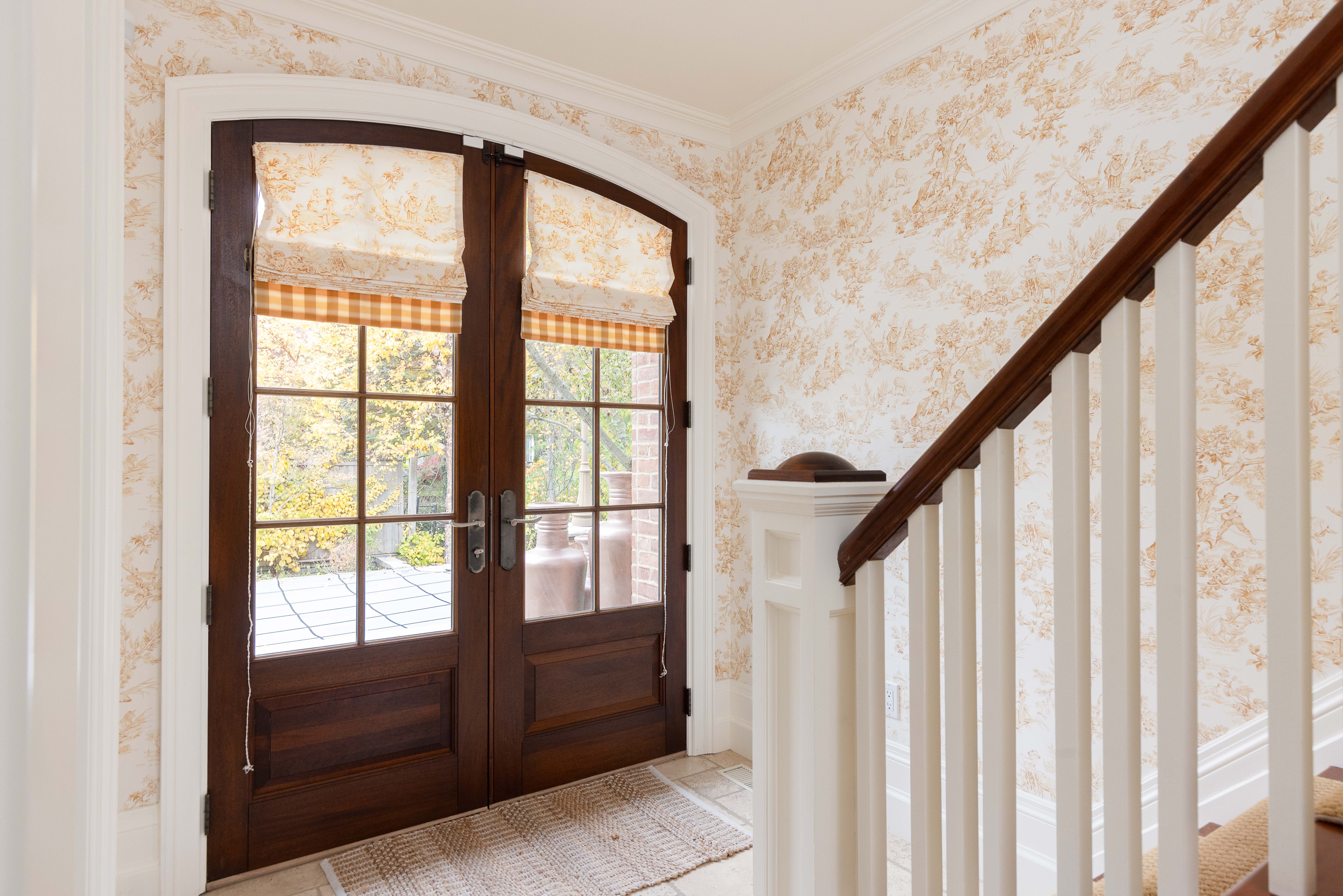 Elegant entryway with double doors and floral wallpaper