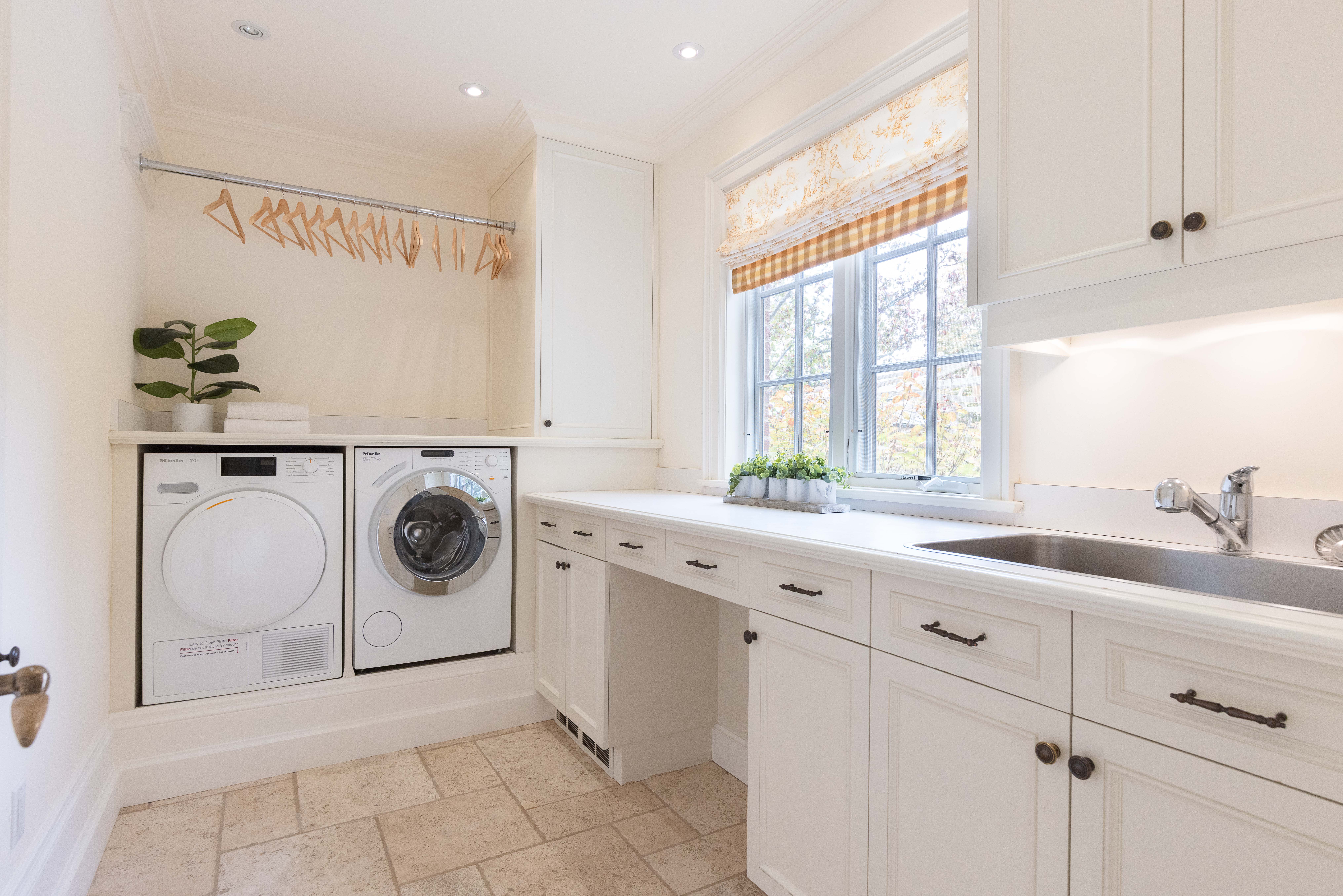 Bright laundry room with white cabinets, washer, dryer, and window.