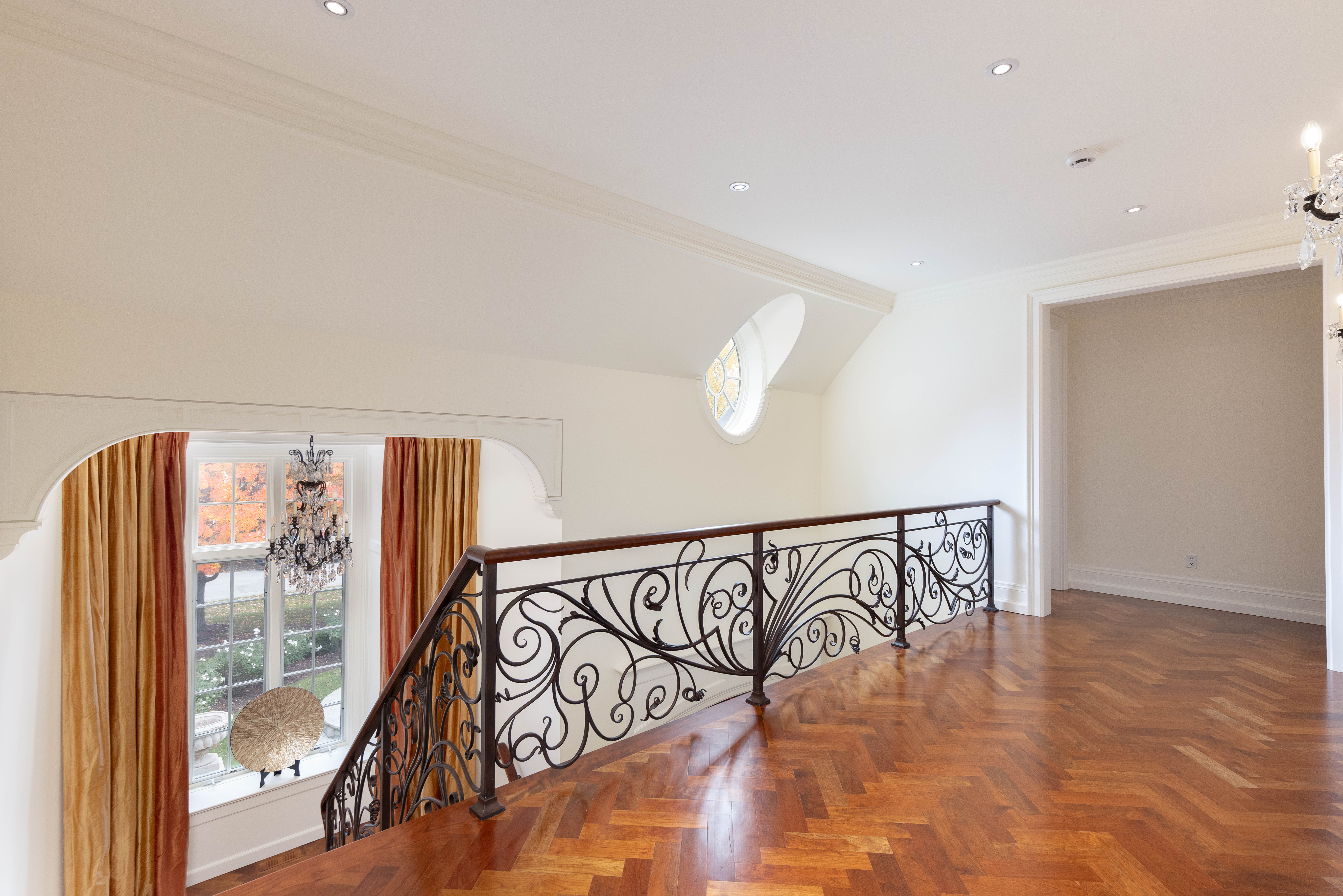 Elegant hallway with wooden flooring and decorative wrought iron railing