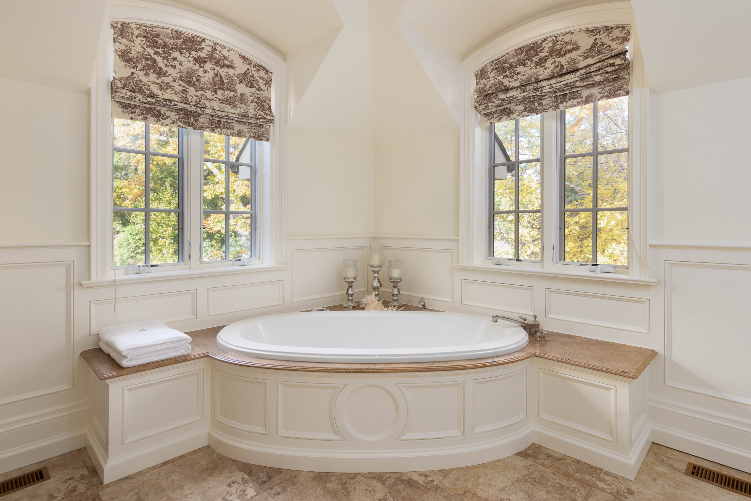 Elegant bathroom featuring a round bathtub and large windows with floral shades