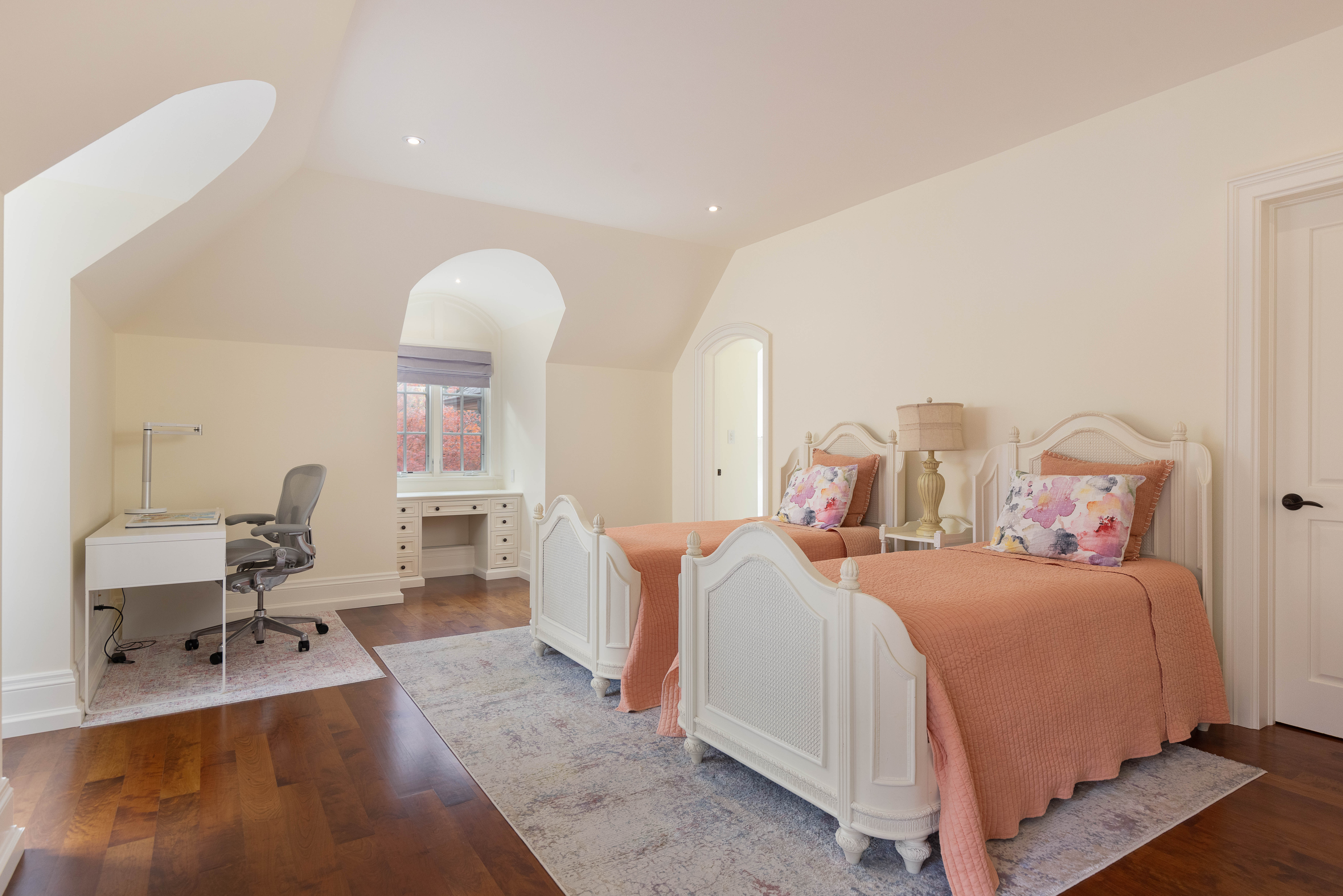 Bright bedroom with two beds, desk, and soft pink accents