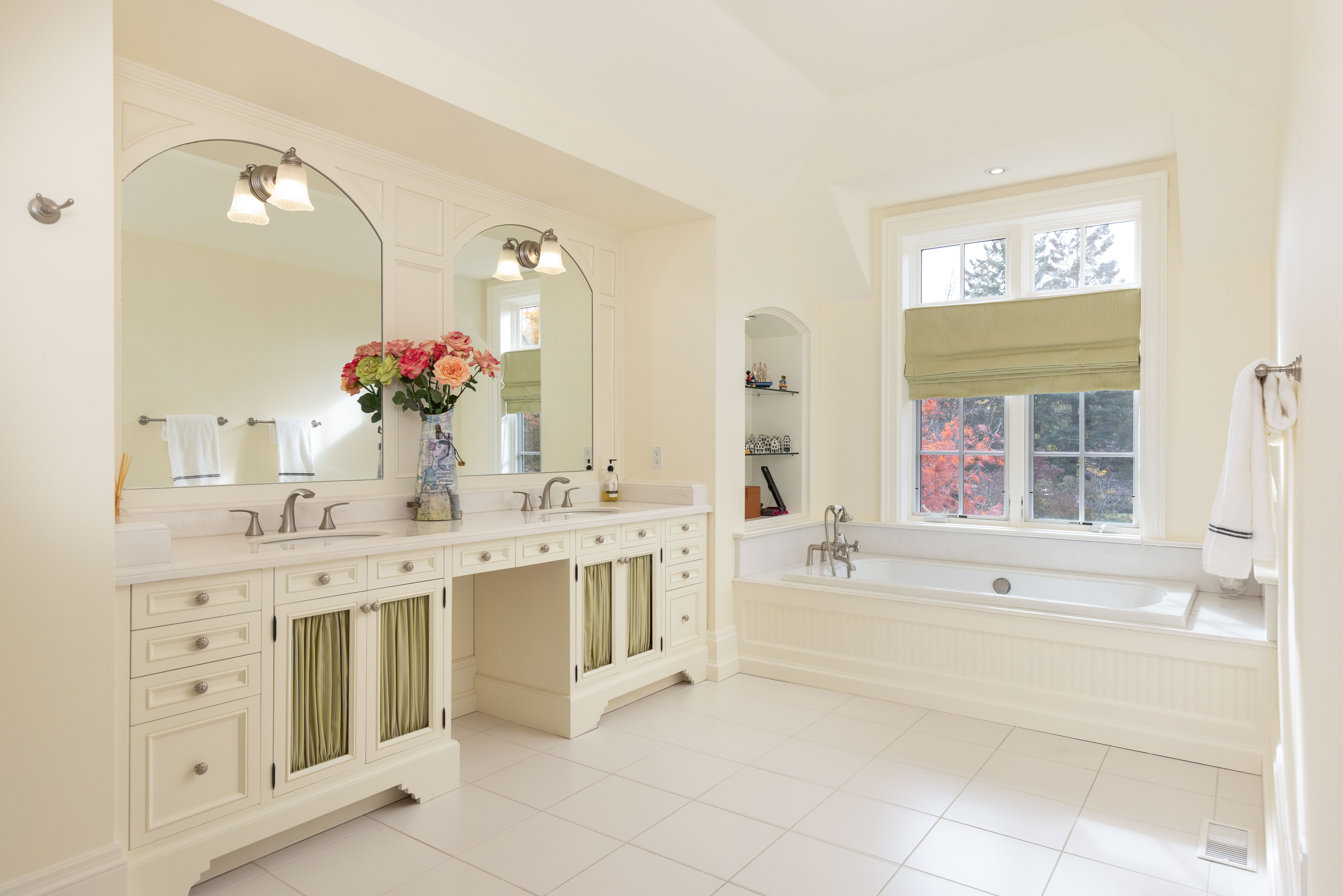 Spacious bathroom with double sinks, floral arrangement, and natural light