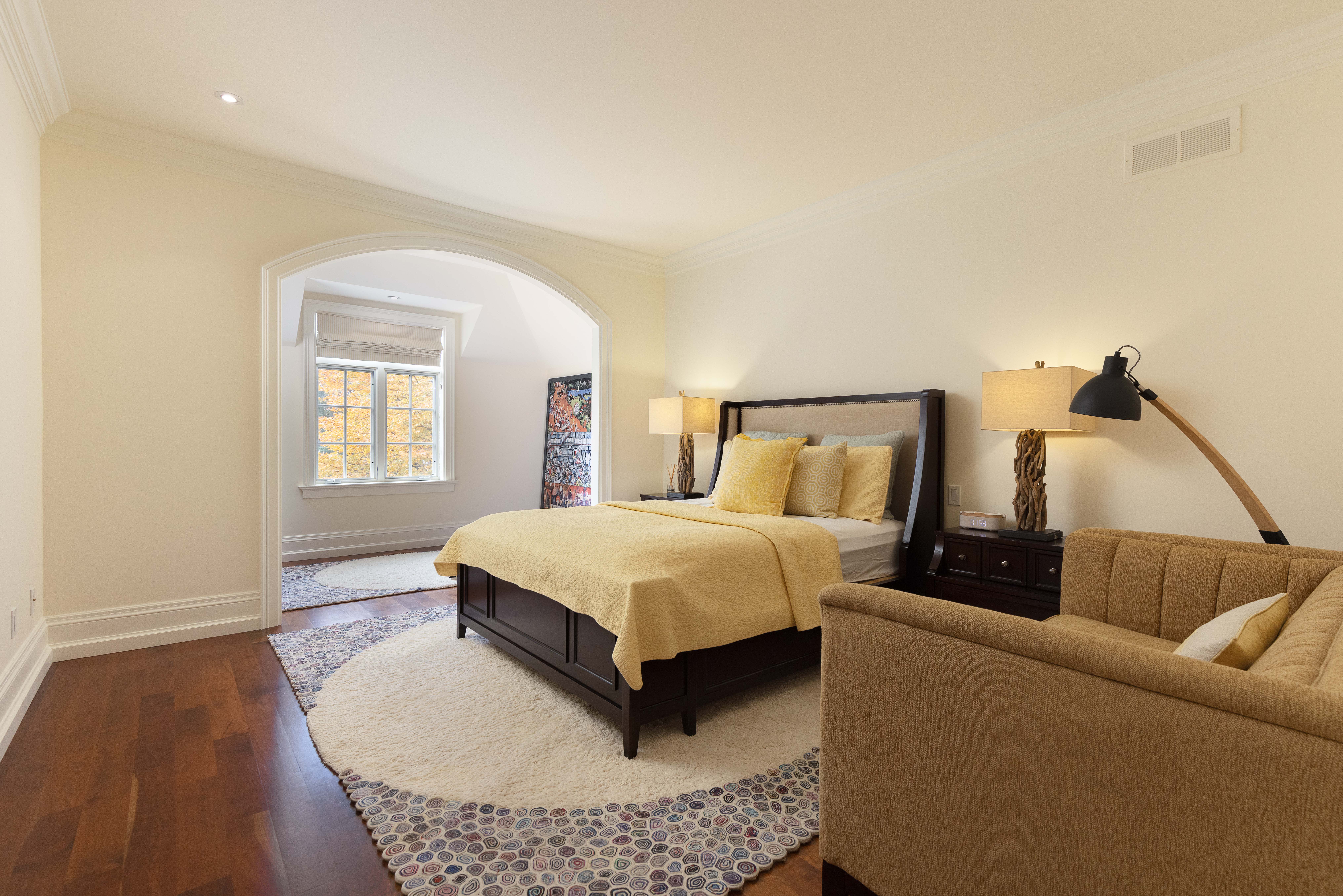 Bright bedroom with yellow bedding, wooden furniture, and a cozy seating area