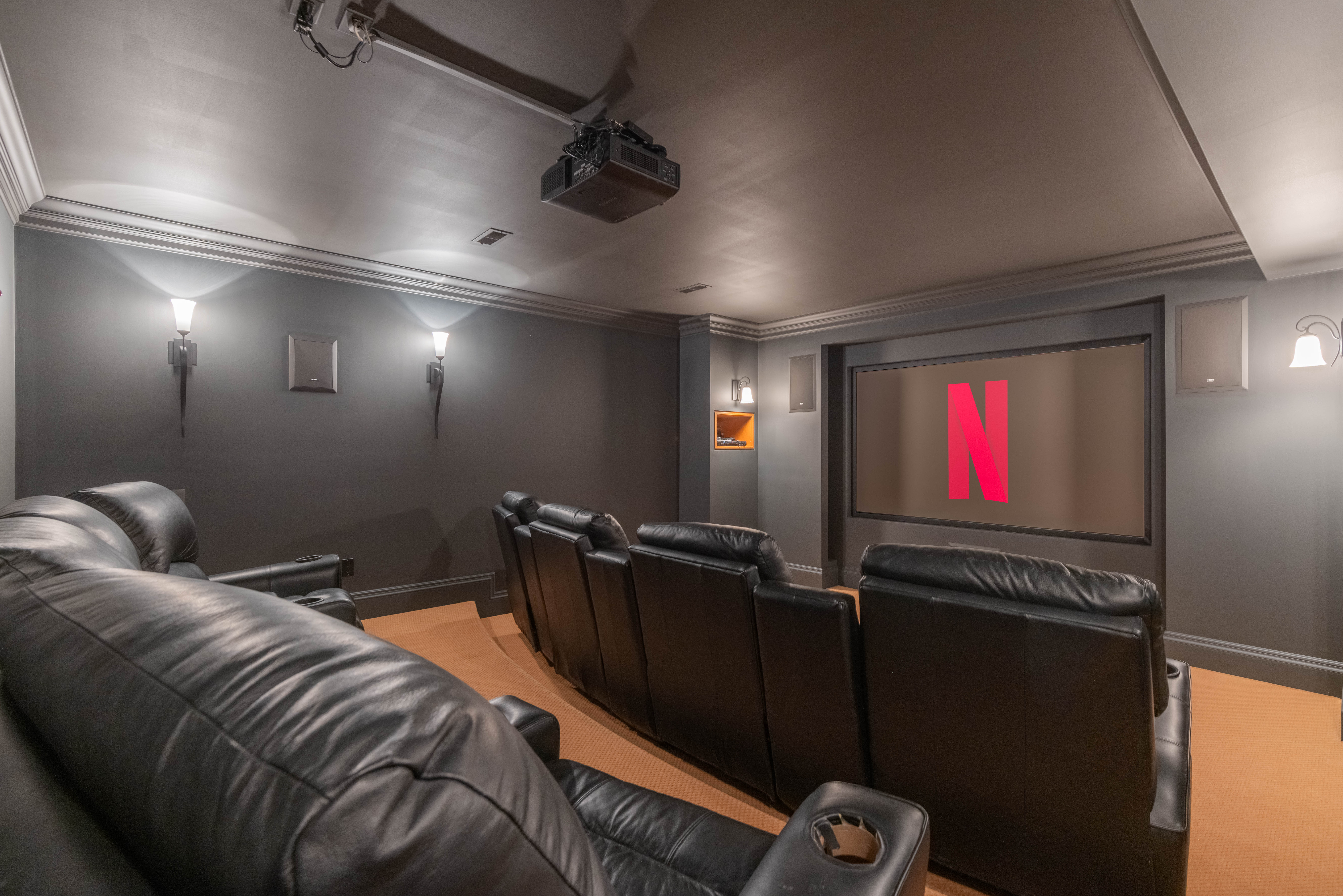 Home theater with black leather seating and a large Netflix screen