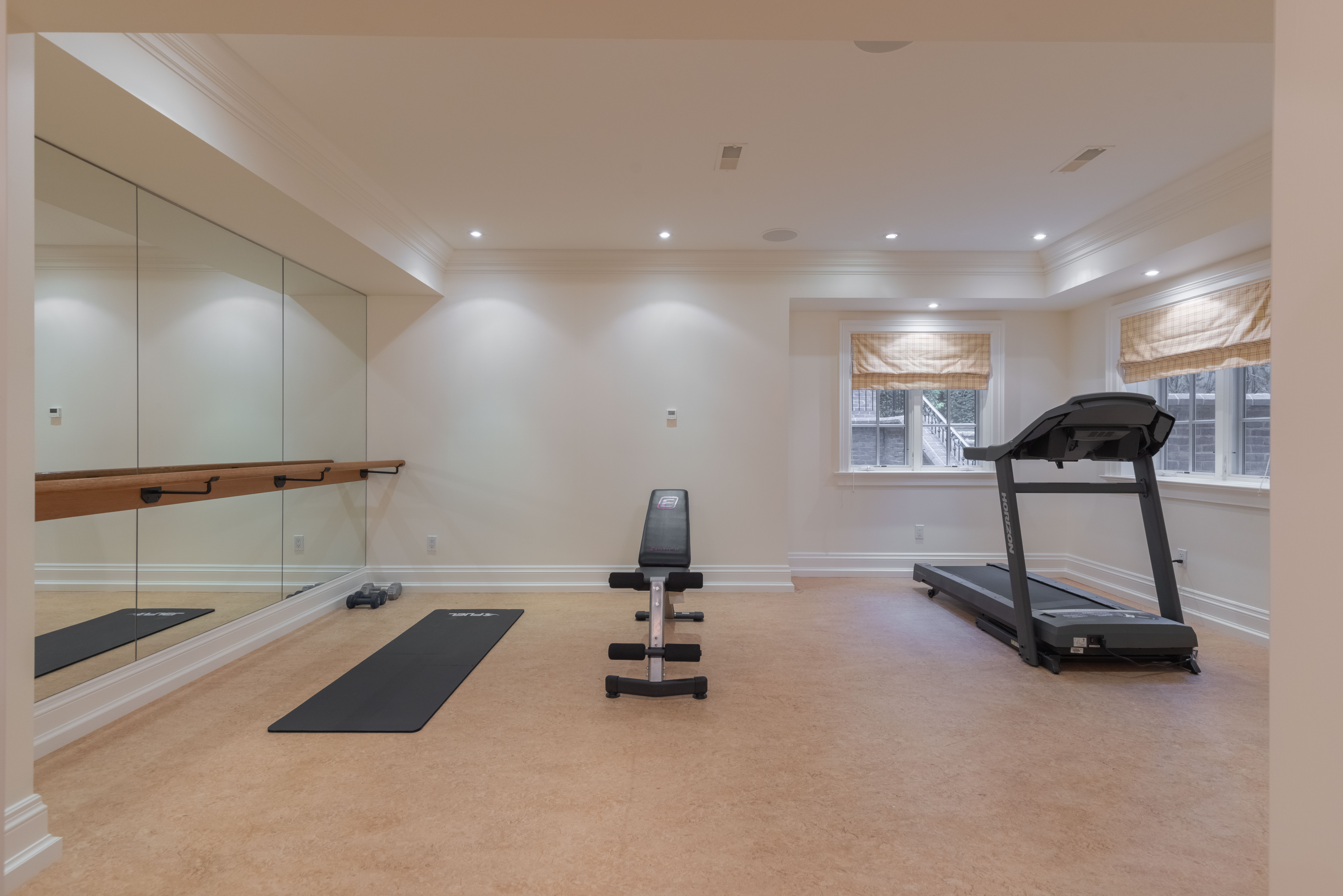 Home gym with treadmill, workout bench, and mirrored wall