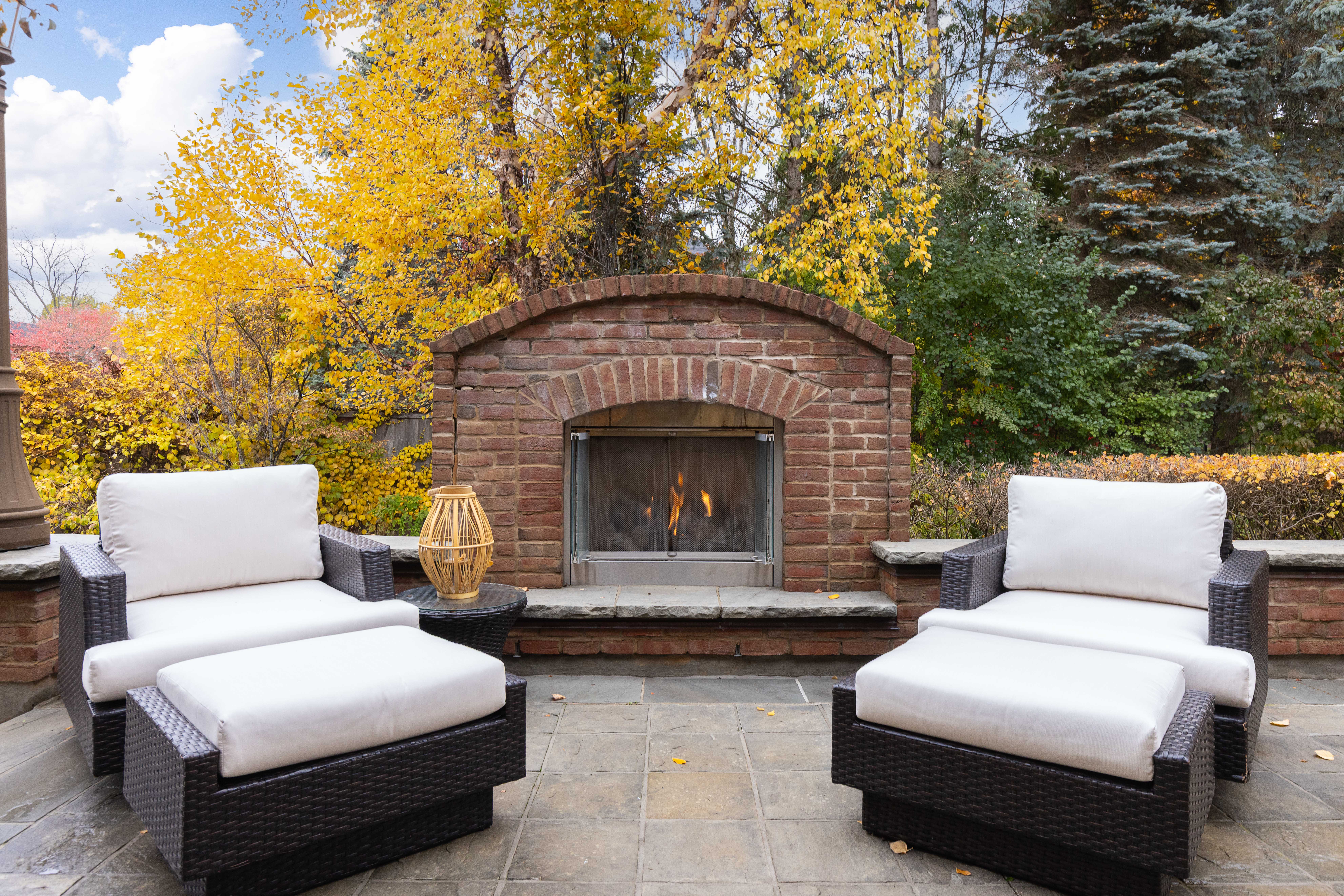 Cozy outdoor seating area with two white chairs and a stone fireplace