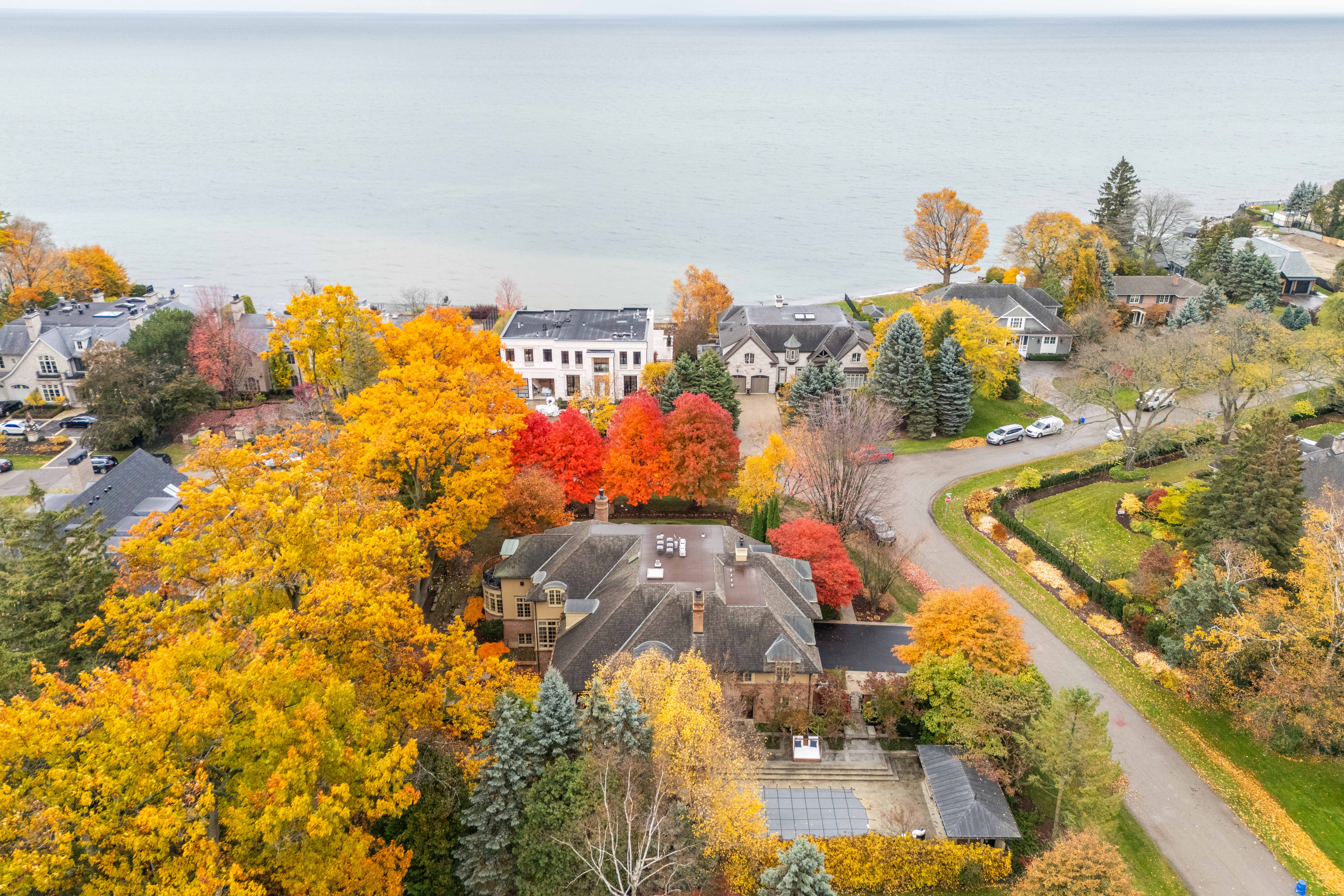 Aerial view of colorful autumn trees near a lake and residential area