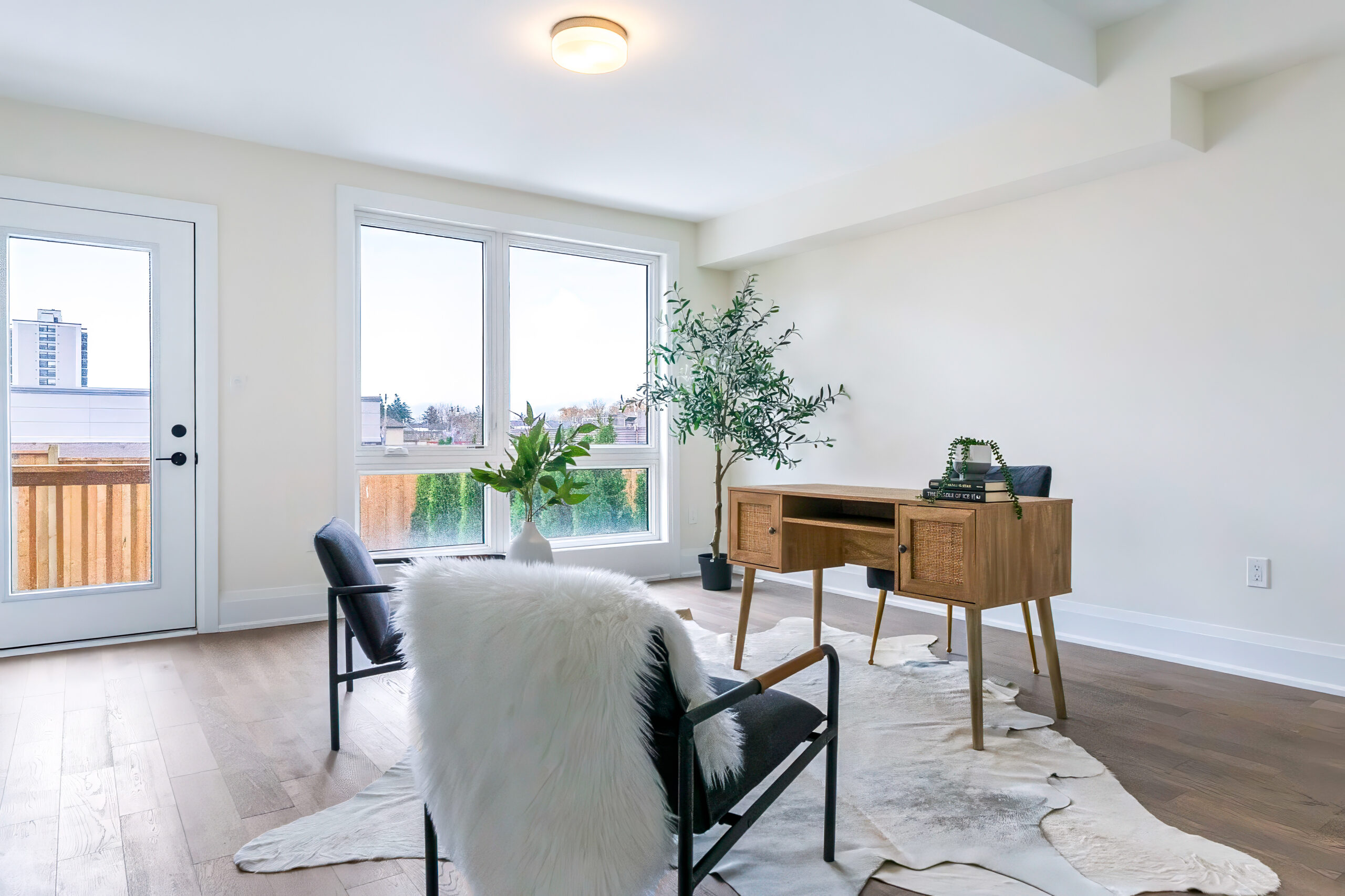 Bright modern office space with wooden desk and chairs, large windows, and plants
