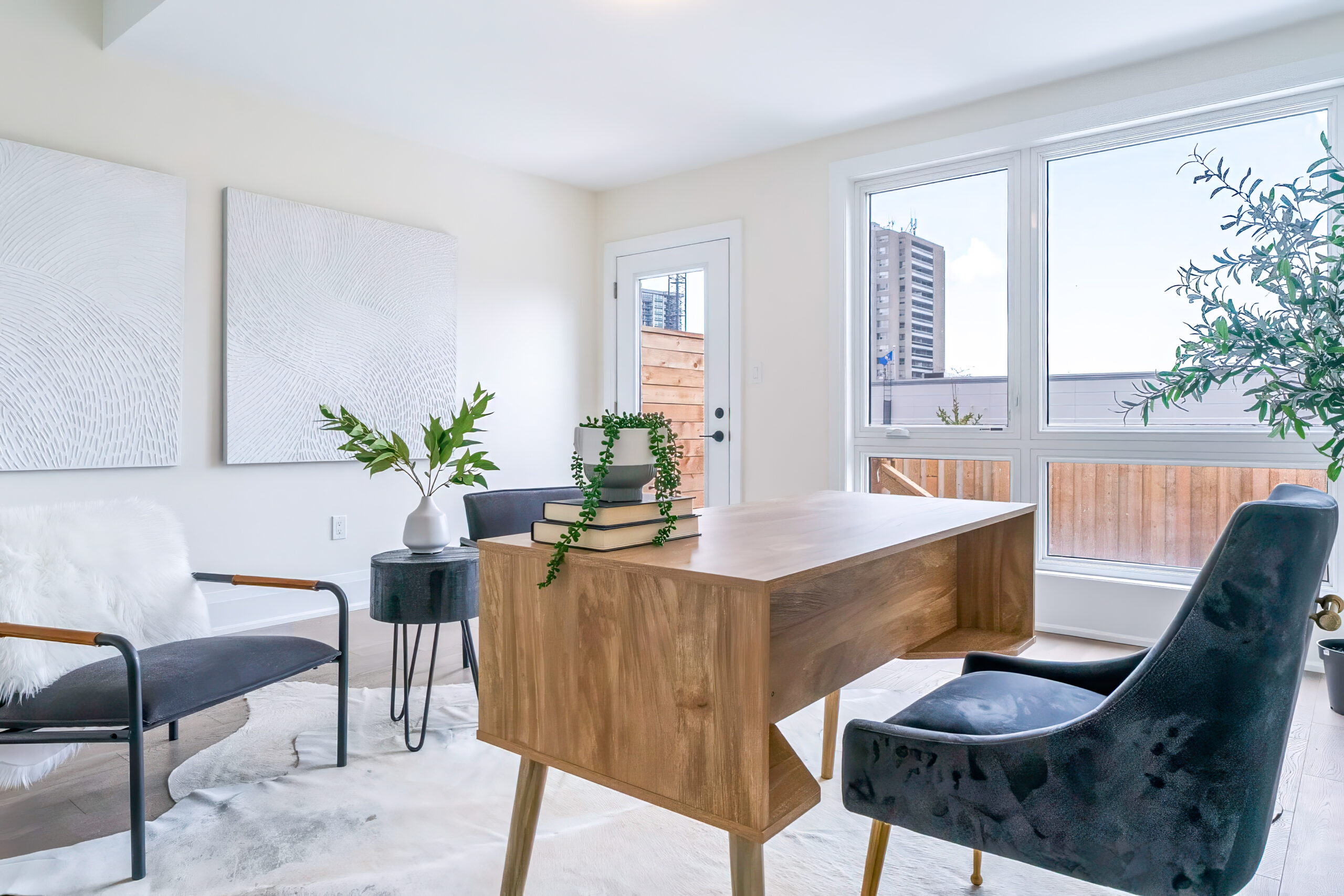 Modern office space with a wooden desk, chairs, and large windows.