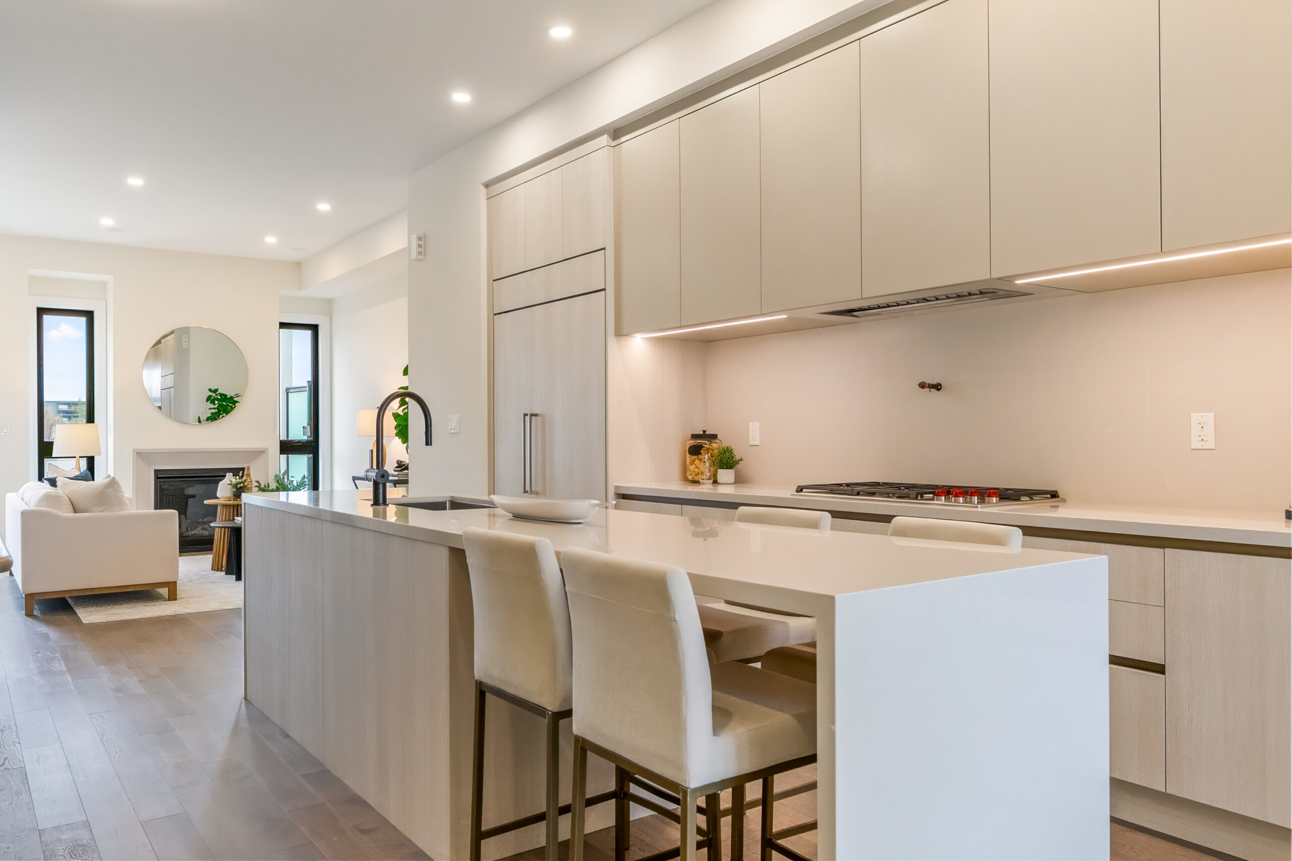 Modern kitchen with light cabinetry and bar seating, open to living area