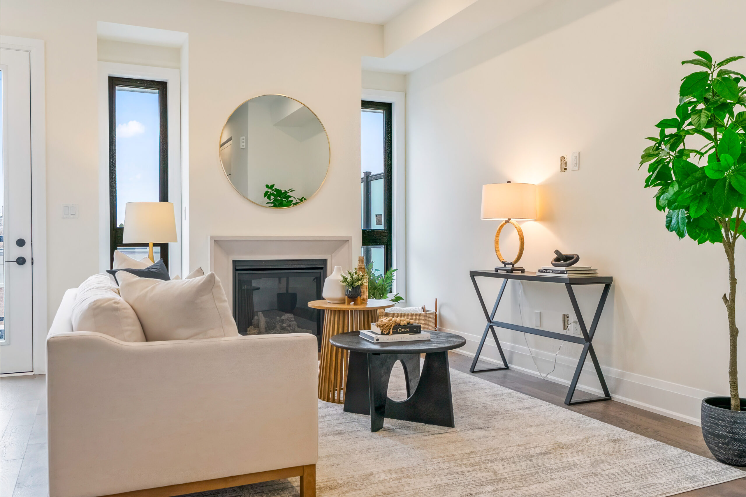 Modern living room with a cozy sofa, round mirror, and plants