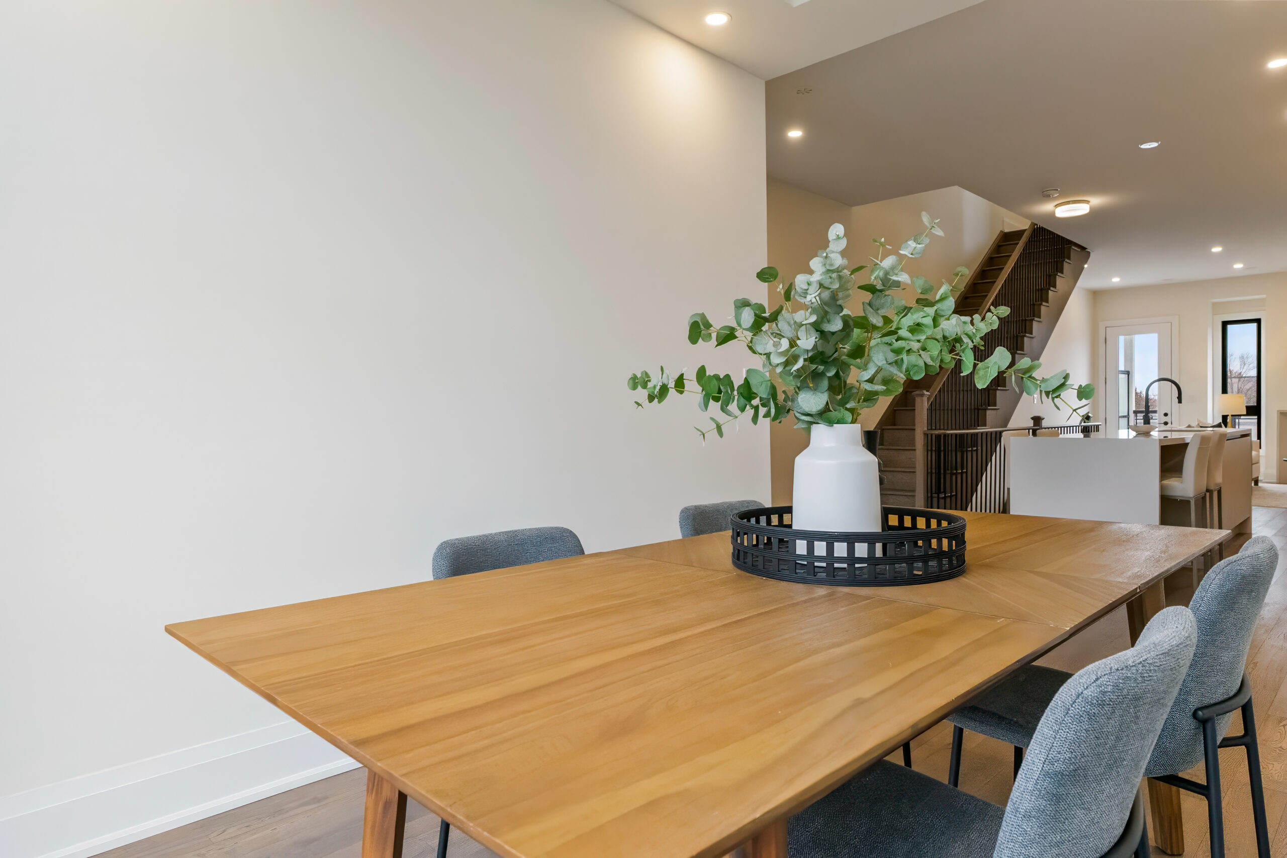 Modern dining area with a wooden table and decorative vase.